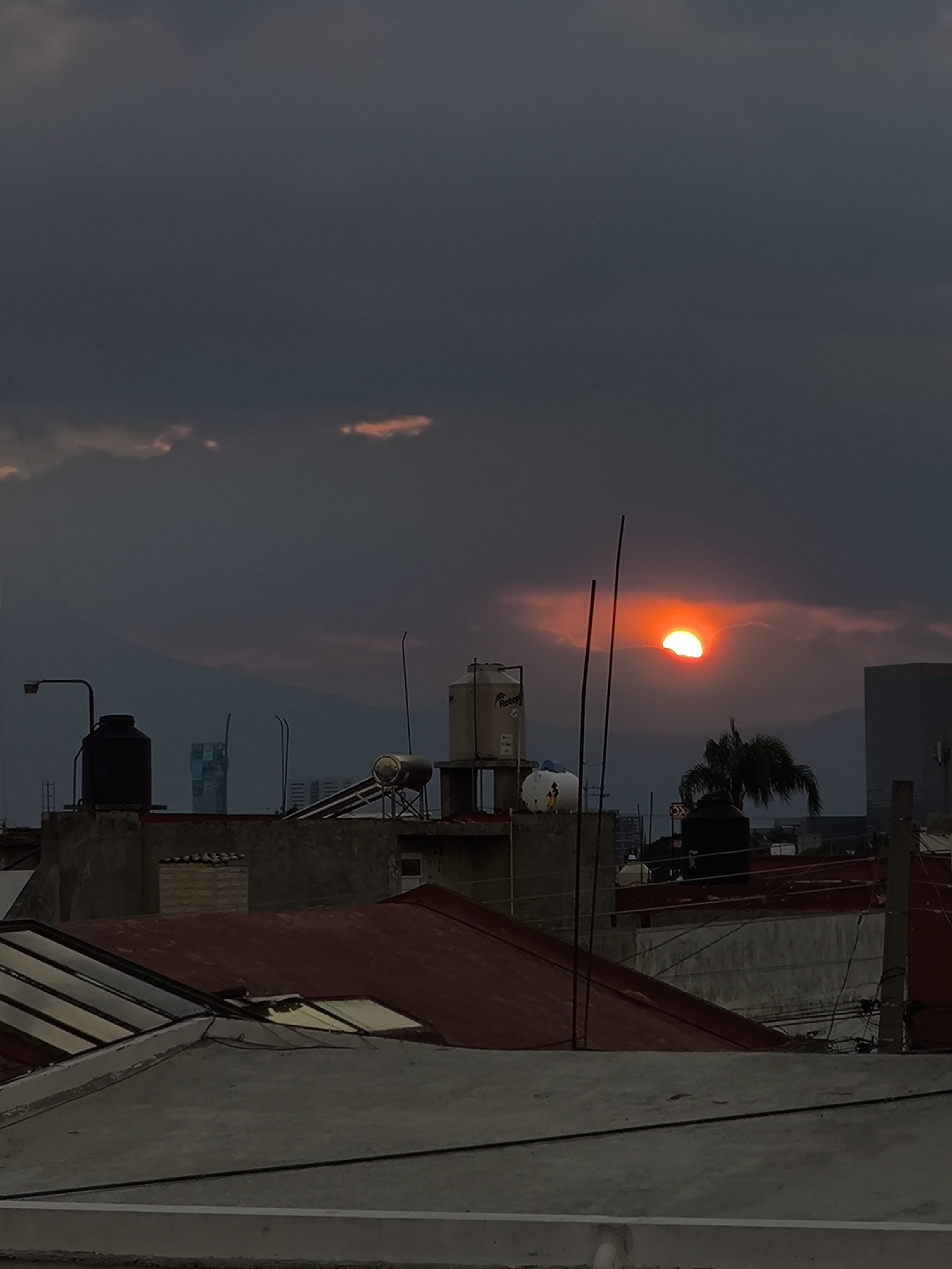 Dramatic sunset observed over Puebla rooftops amid stormy clouds
