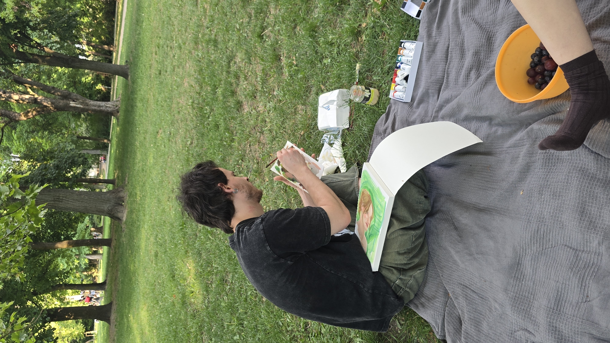 Artist paints outdoors in Budapest park on sunny afternoon