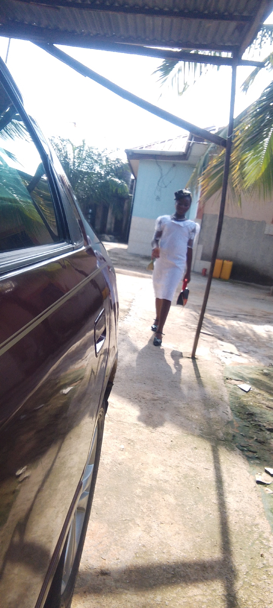 White-dressed group near a maroon sedan in Madalla