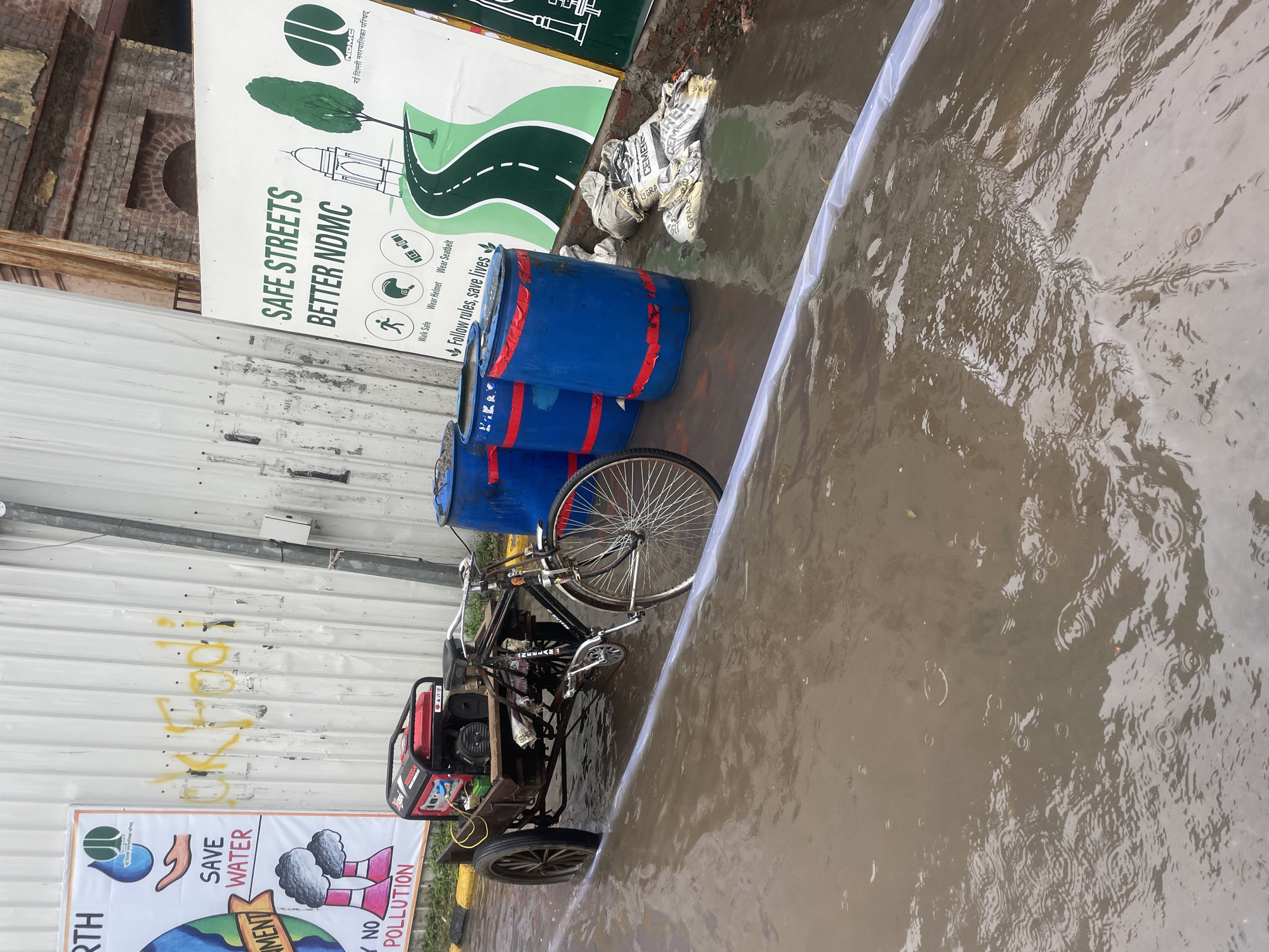 Flooded New Delhi street with submerged cart and active water pump
