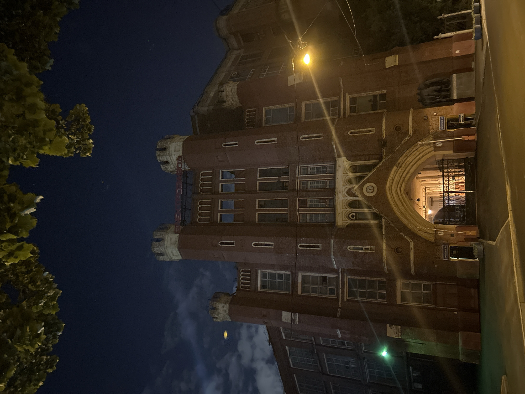 Gothic brick building lit up at night, two angles