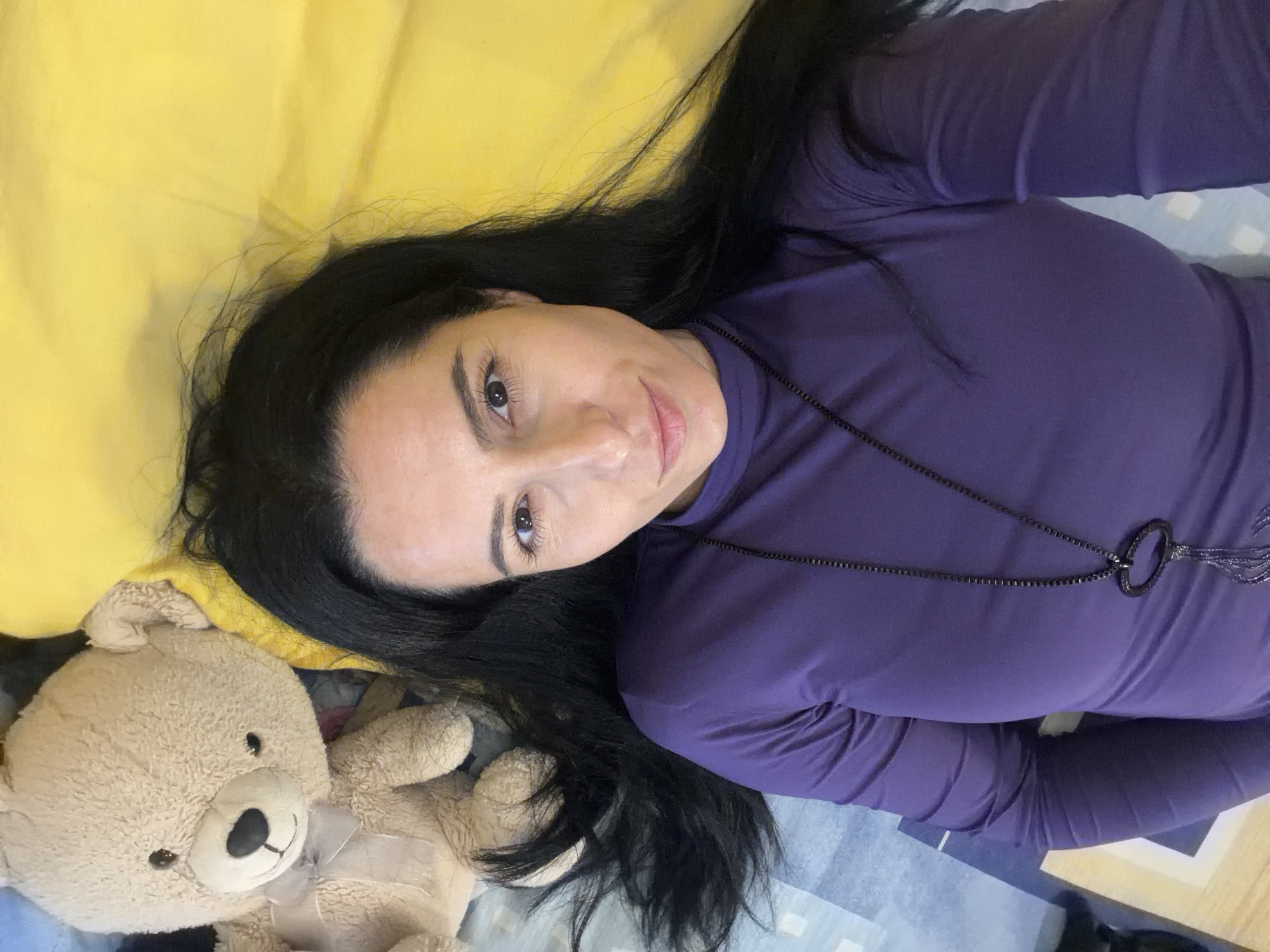 Woman poses with teddy bear on bed in Bulgaria