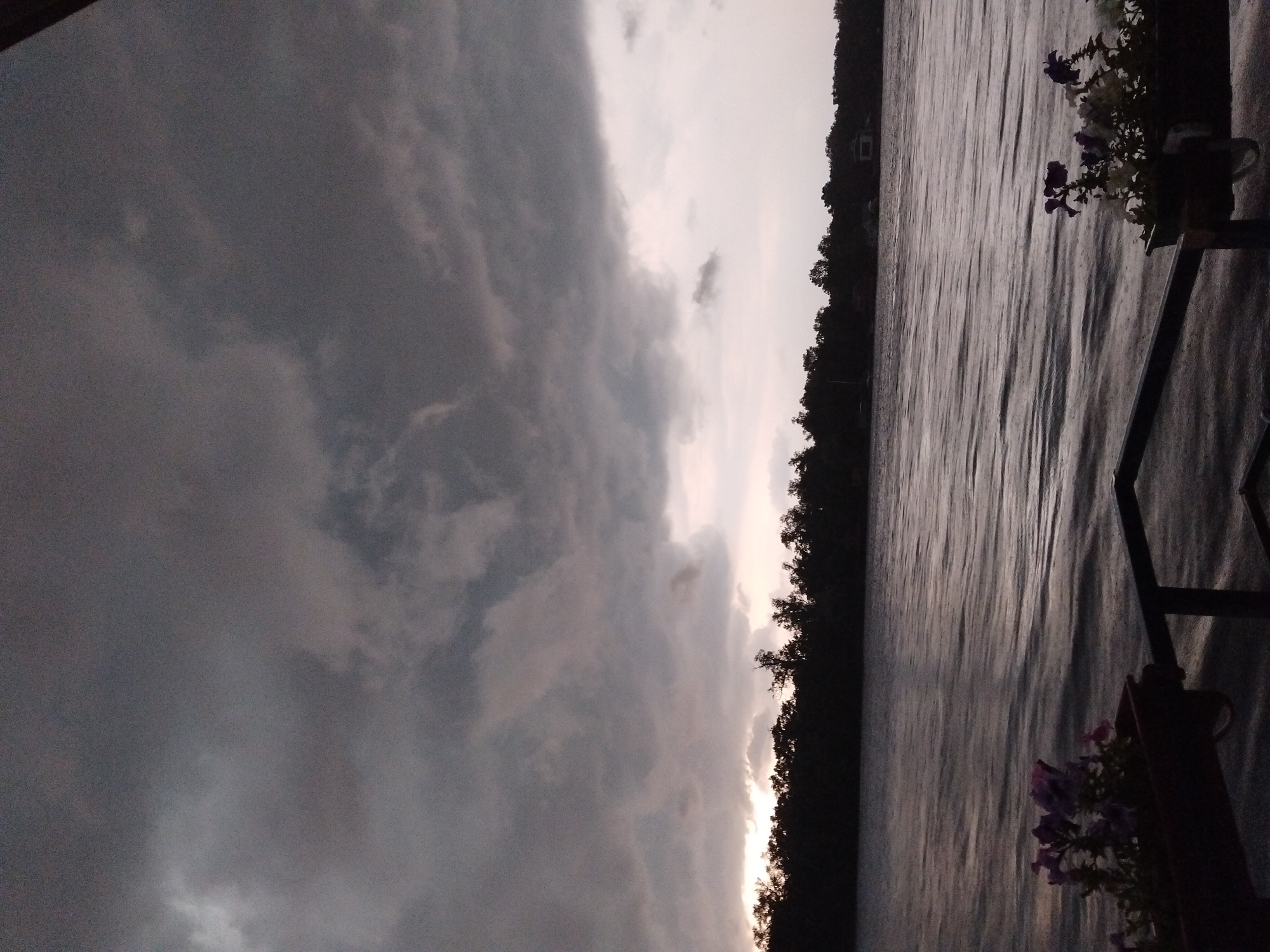 Storm rolls over the Dnipro, watched from a riverside deck