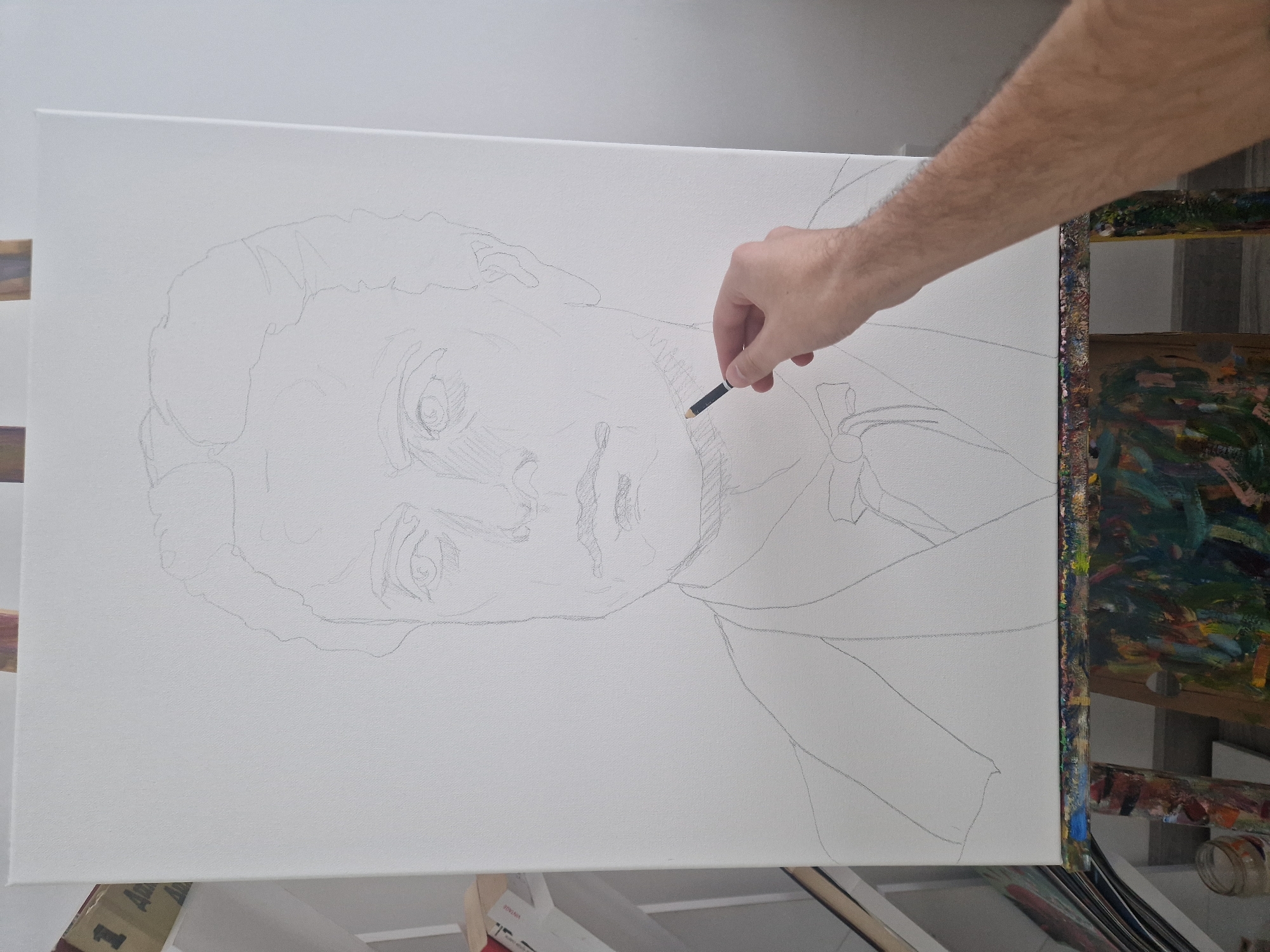 Artist sketches male portrait on easel indoors