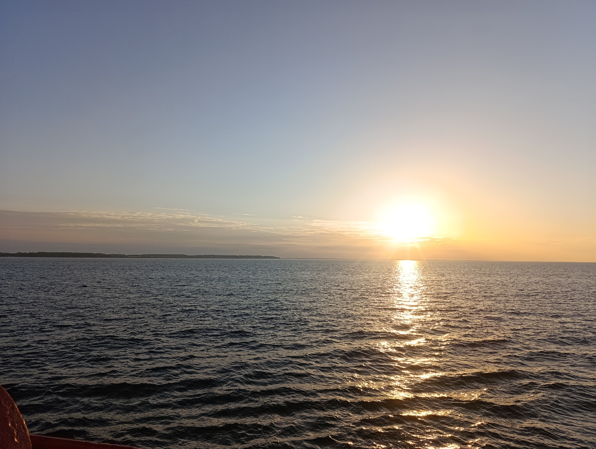 Calm water reflects a clear-sky sunset at golden hour.