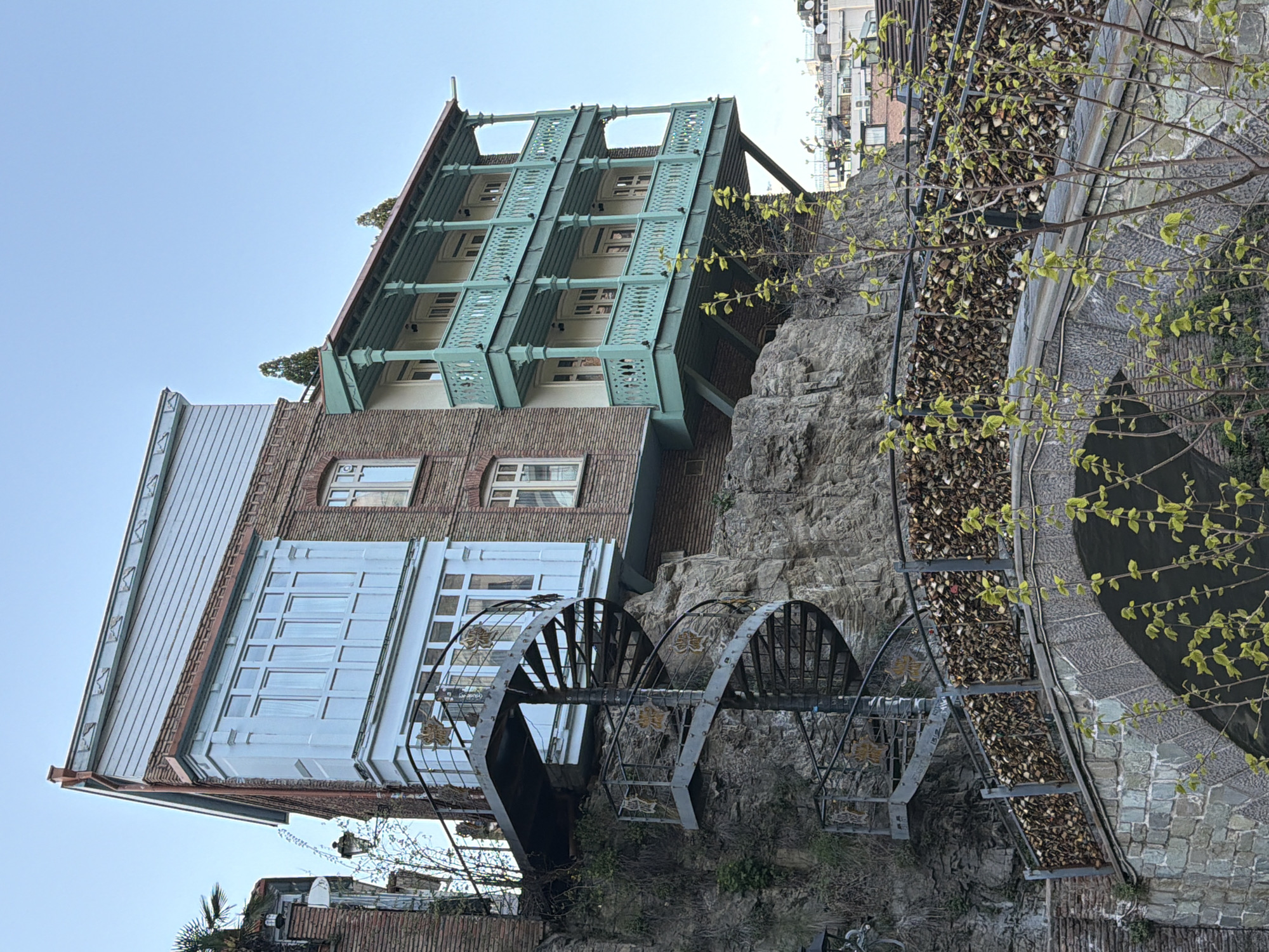 Multi-story cliff building with green balconies documented in Tbilisi