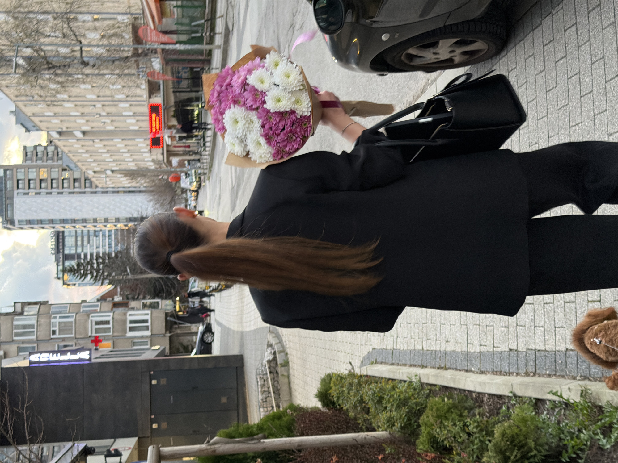 Woman with flowers walks near Sofia hospital at dusk
