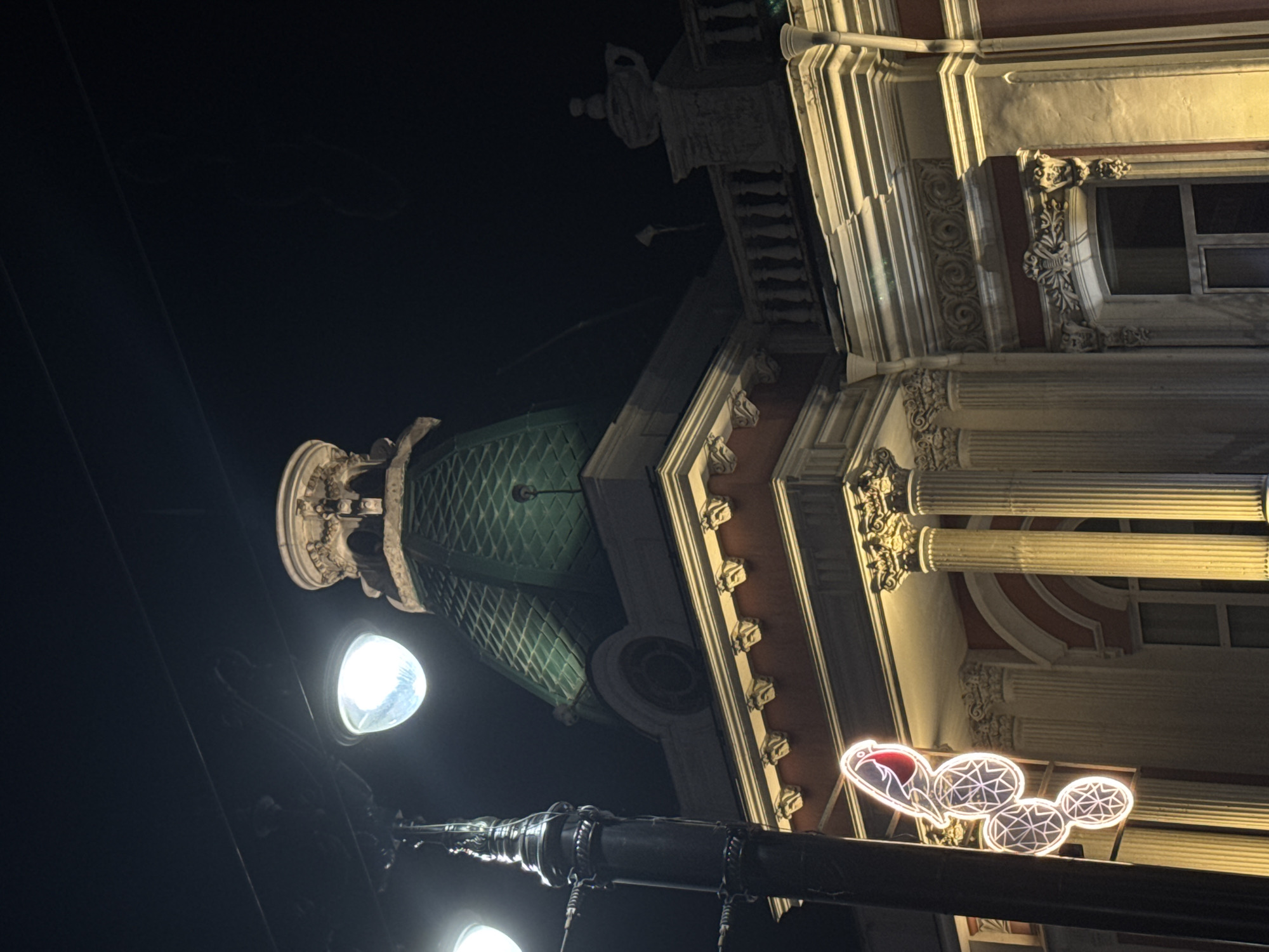 Historic neoclassical building with green dome photographed at night in Omsk