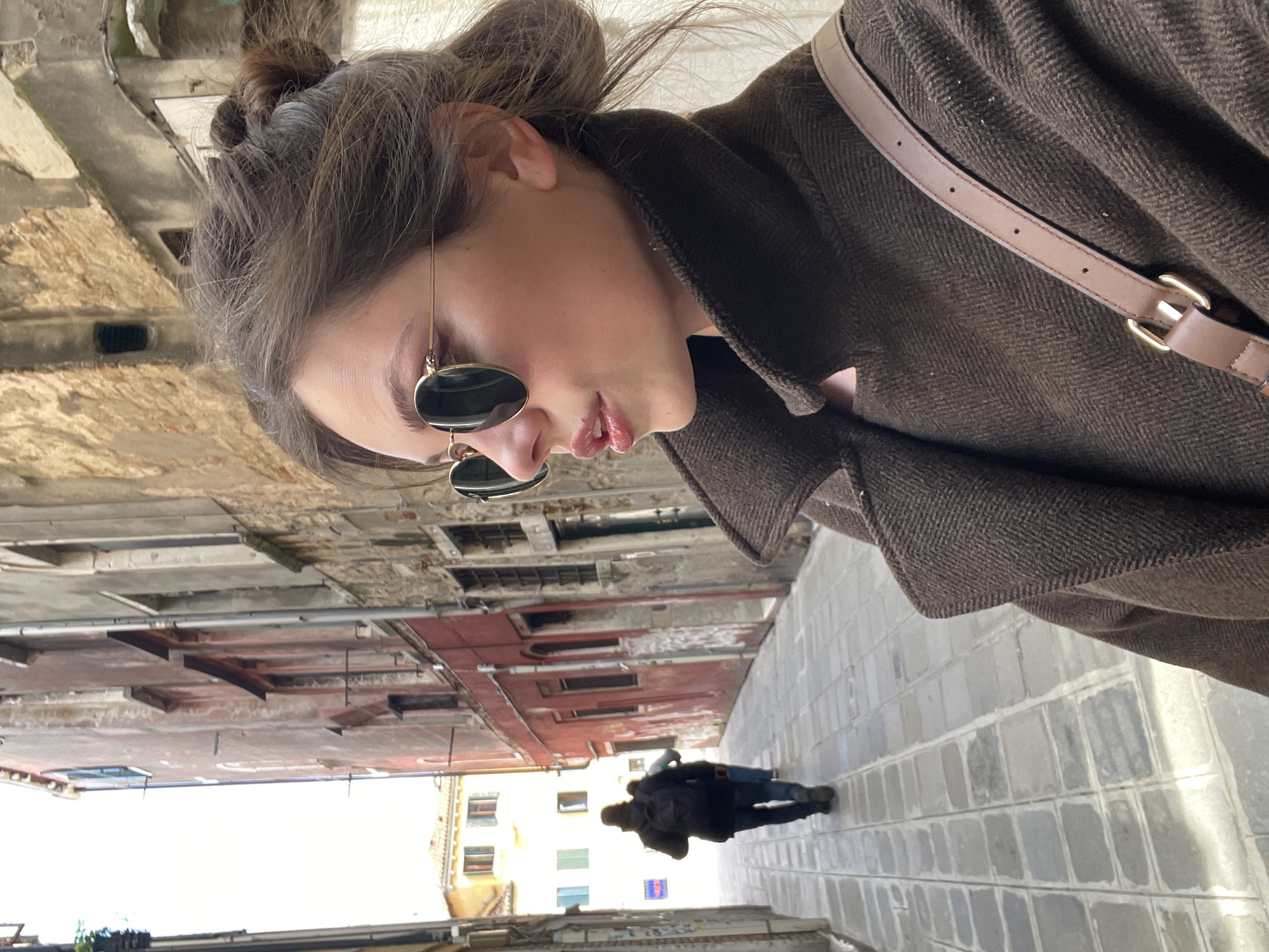 Tourist photographed on narrow Venice street amid historic architecture