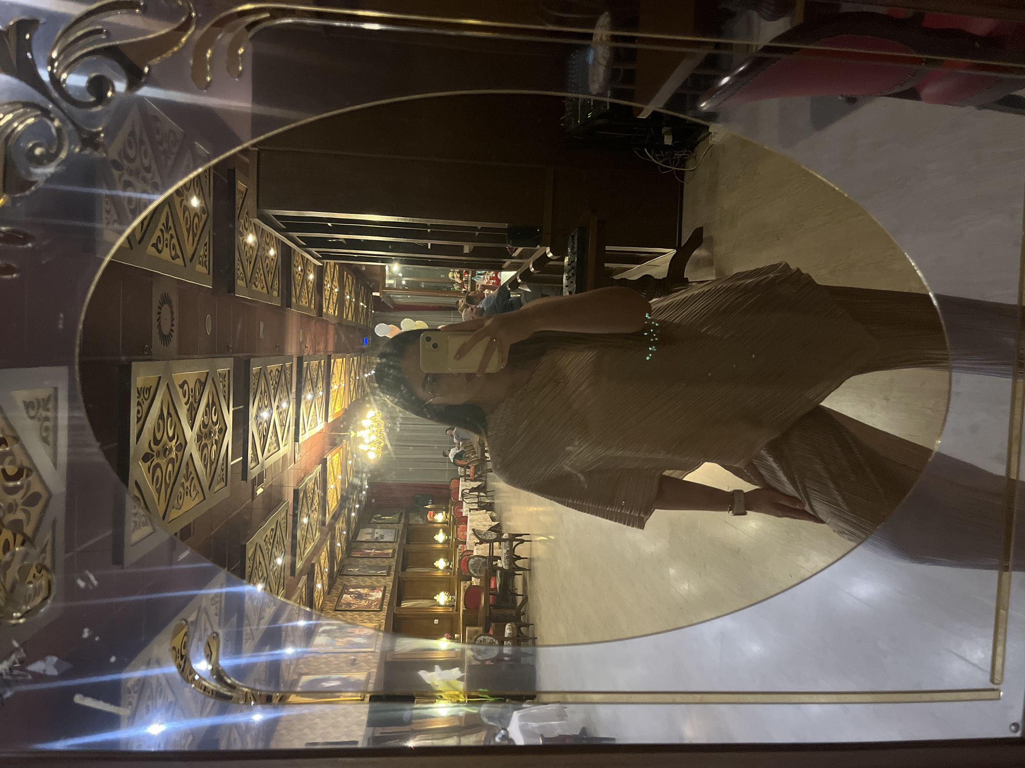 Woman takes selfie in ornate gold mirror at decorated venue