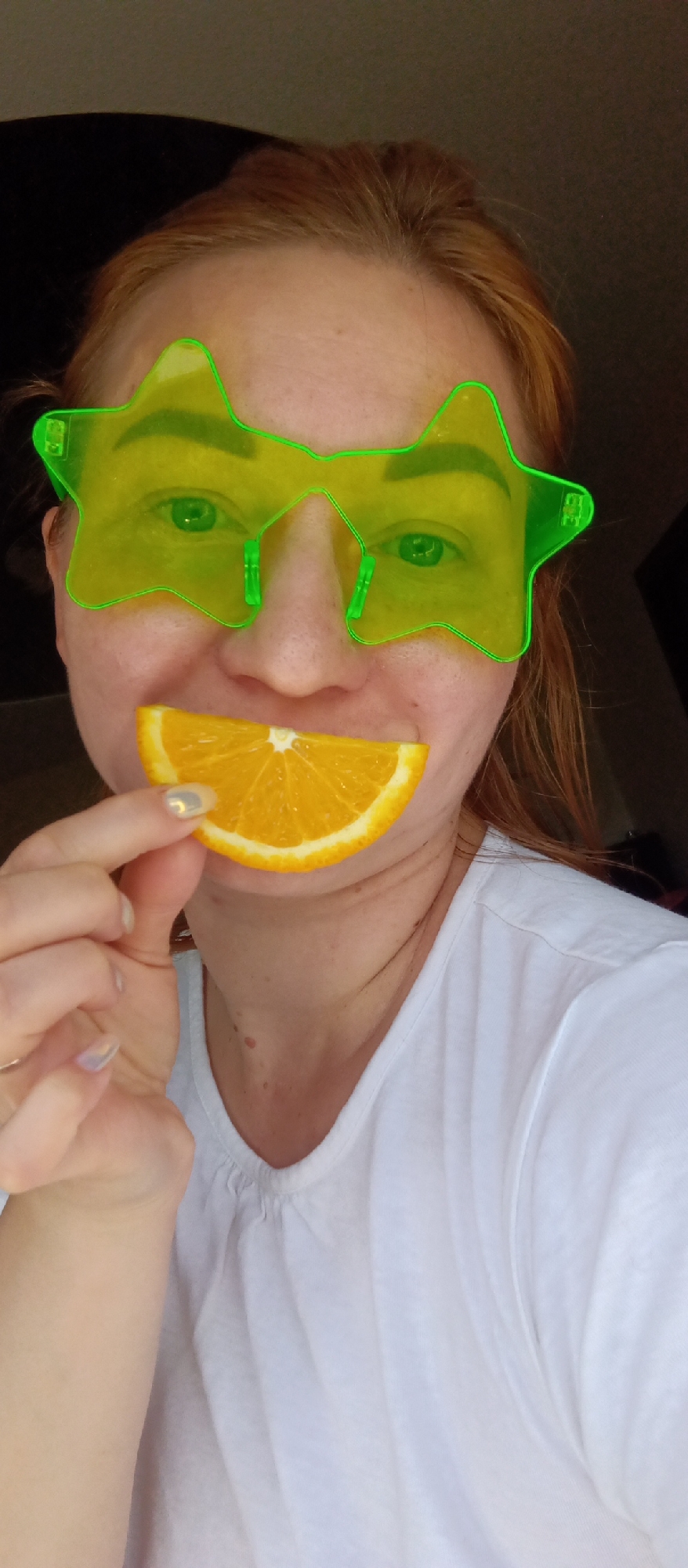 Person in star sunglasses poses indoors with orange slices