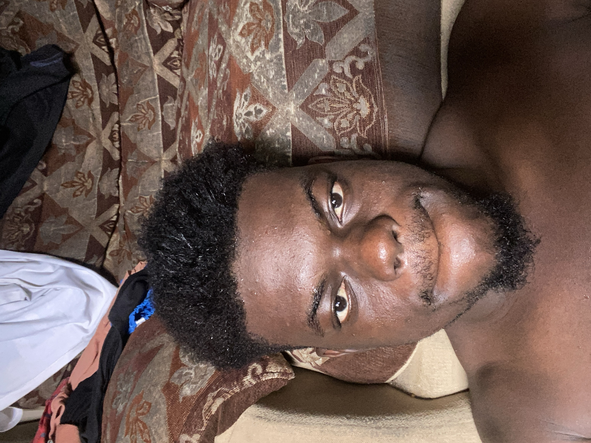 Man rests on patterned fabric surface among clothing items