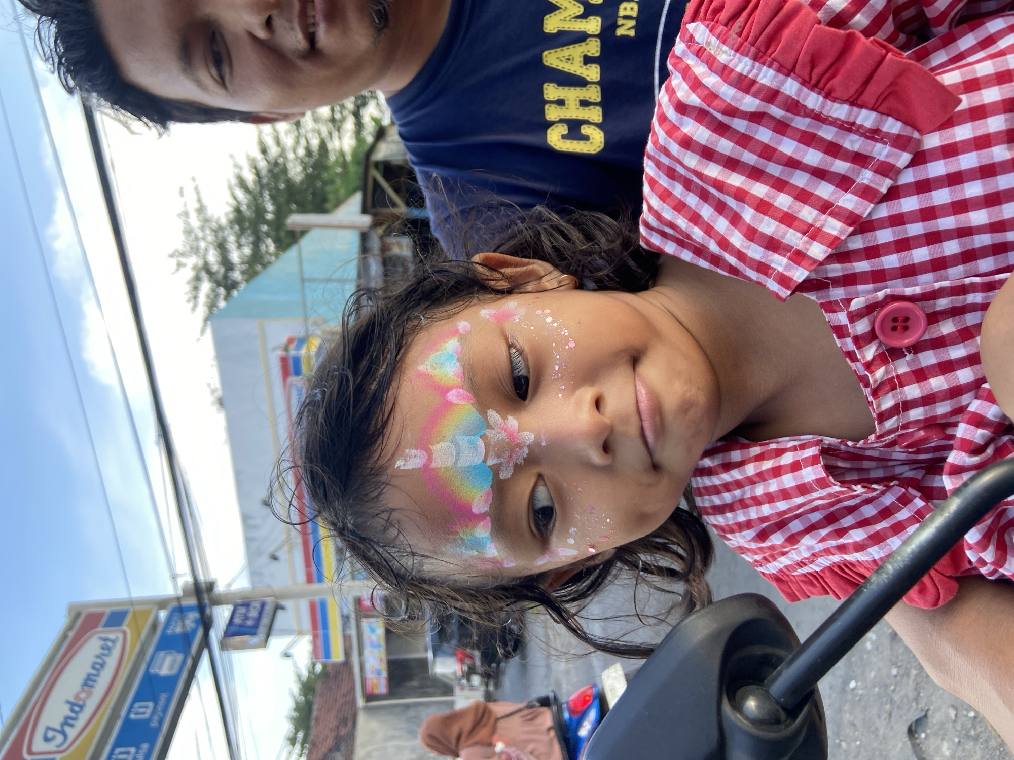 Father, daughter with face paint ride motorcycle in Indonesia