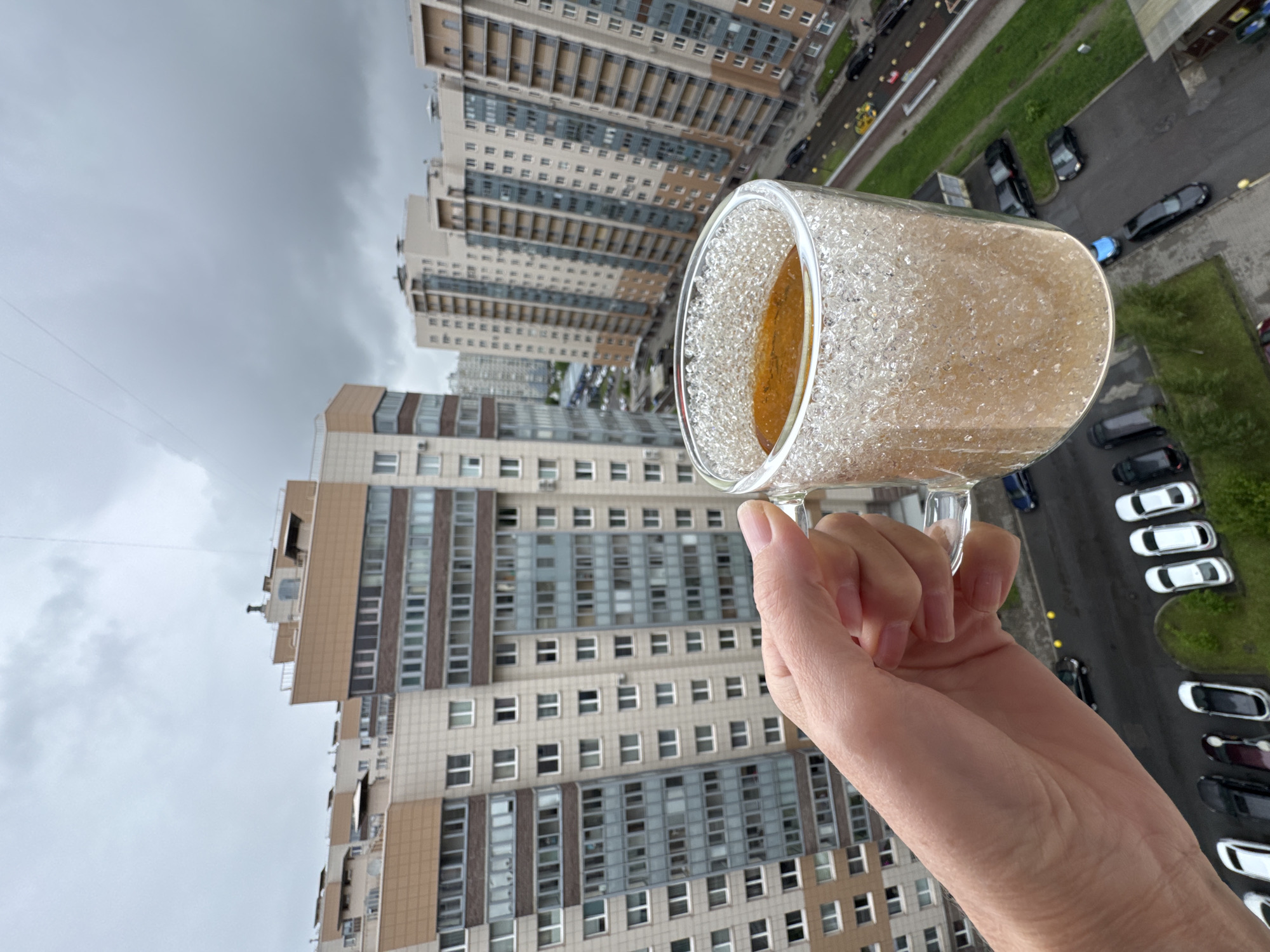 Person holds specialty tea drink amid urban overcast morning