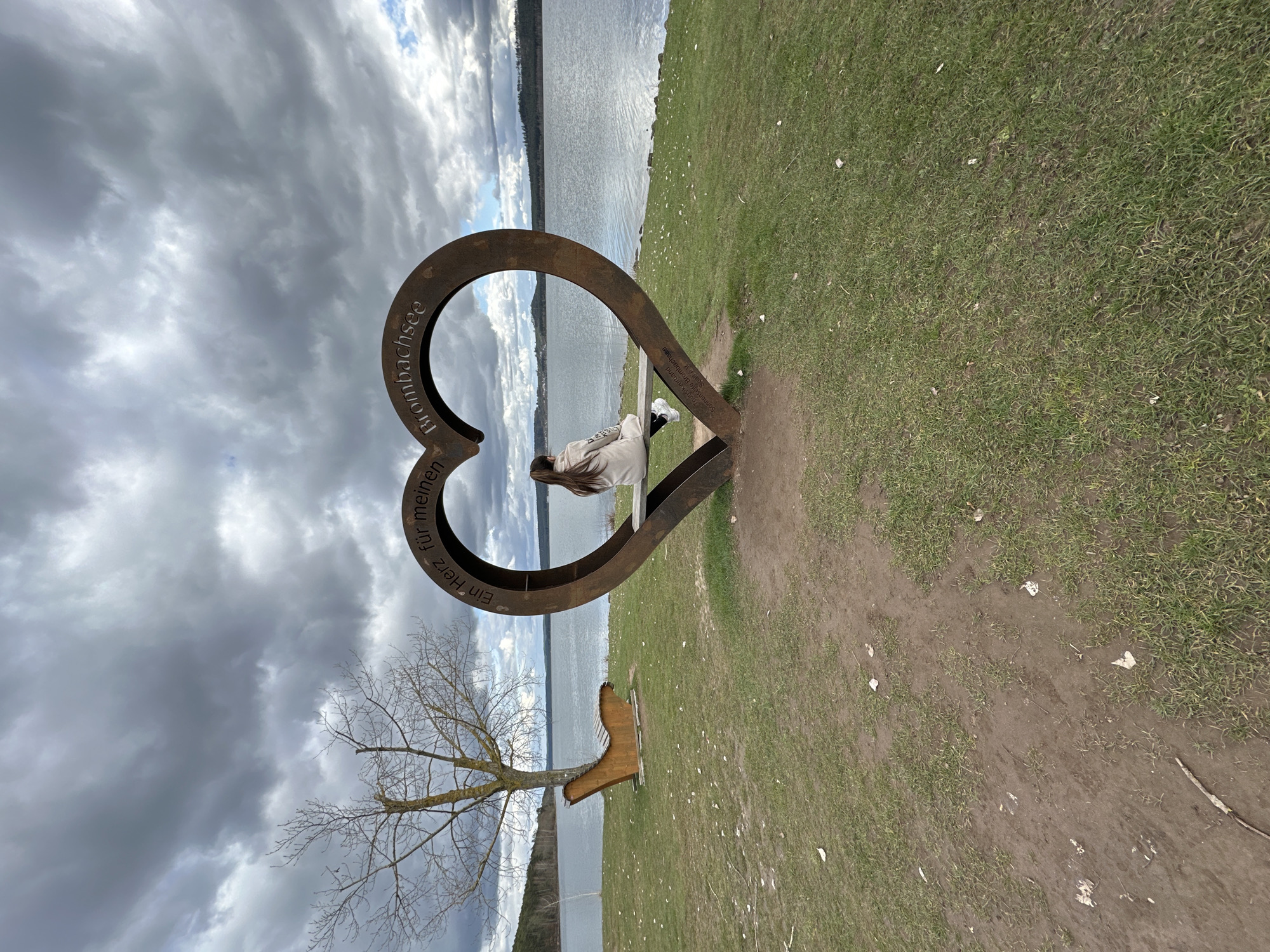 Woman sits on heart-shaped bench beside lake in Spalt