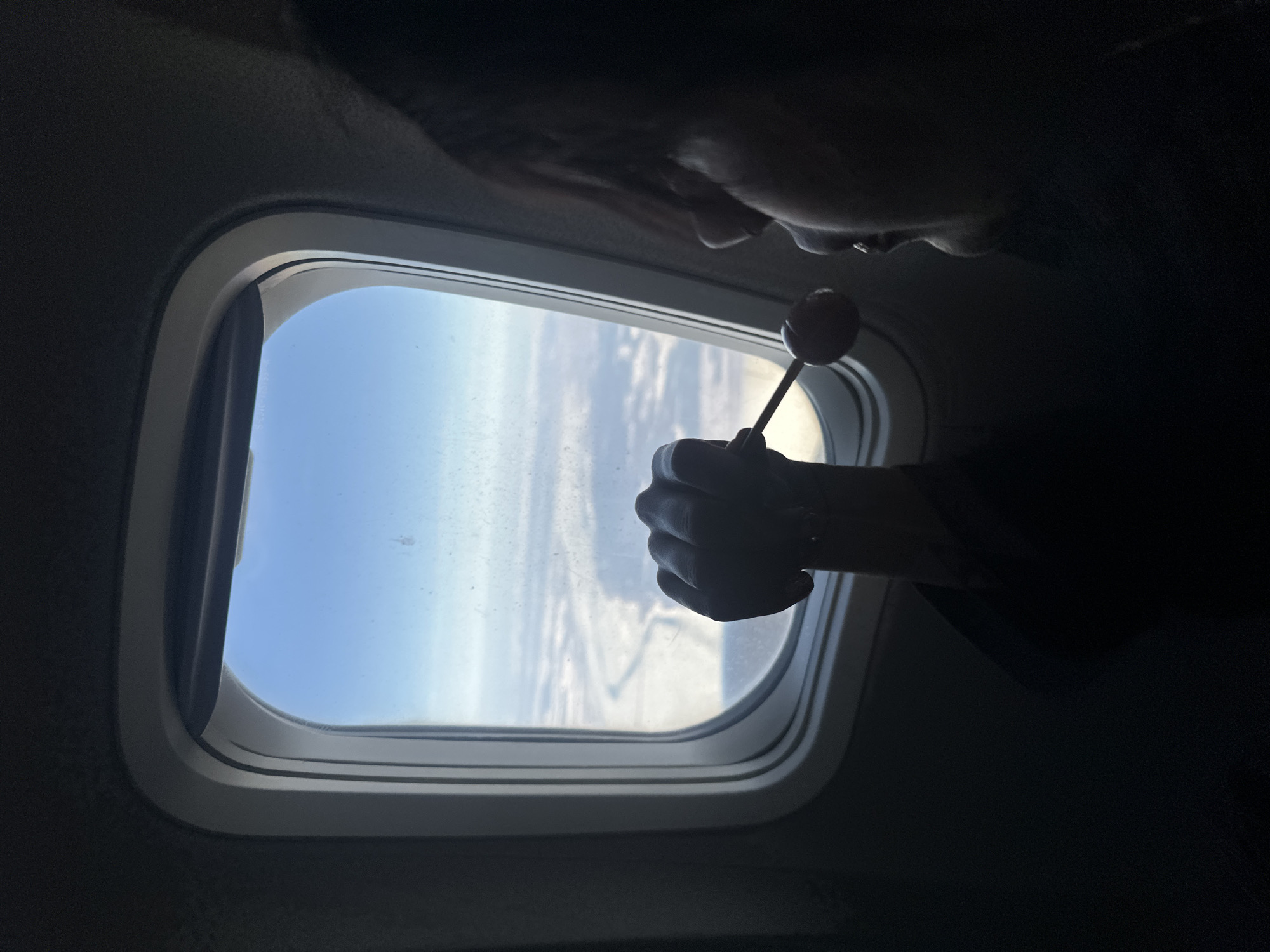 Airplane passenger enjoys lollipop while gazing out window