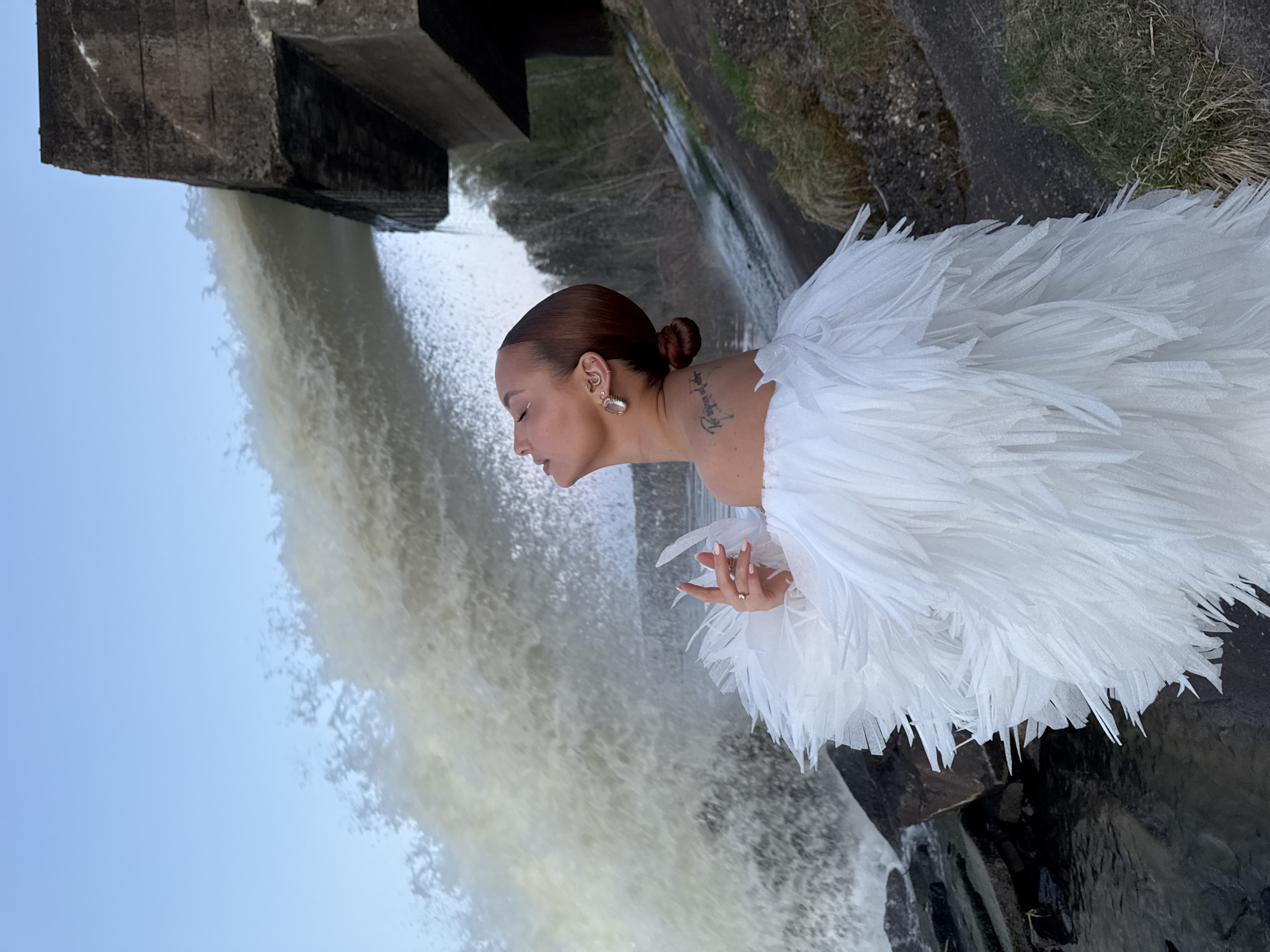 Woman poses near waterfall at dam site in Noviy, Russia