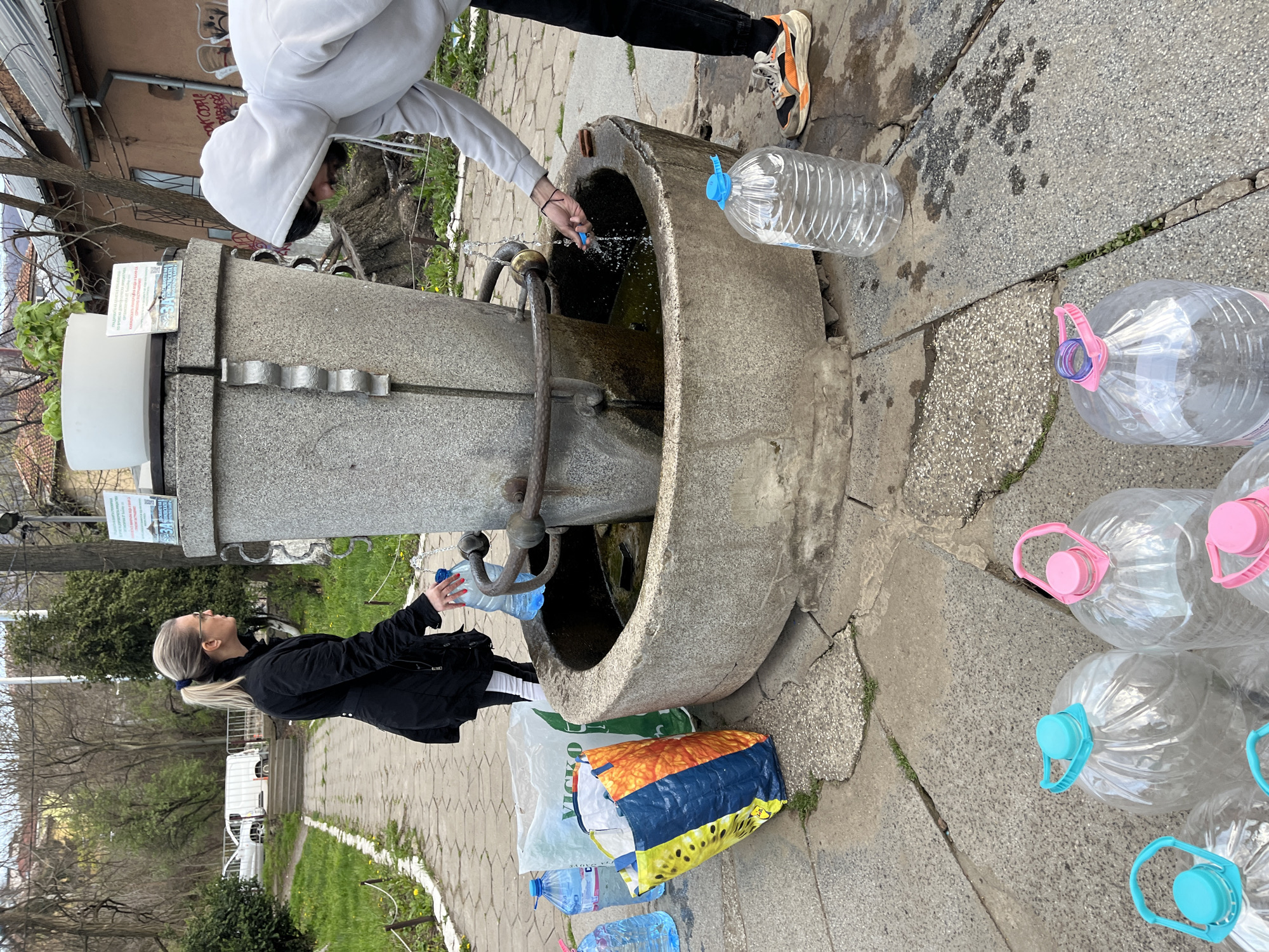 Two people fill water bottles at Sofia public fountain
