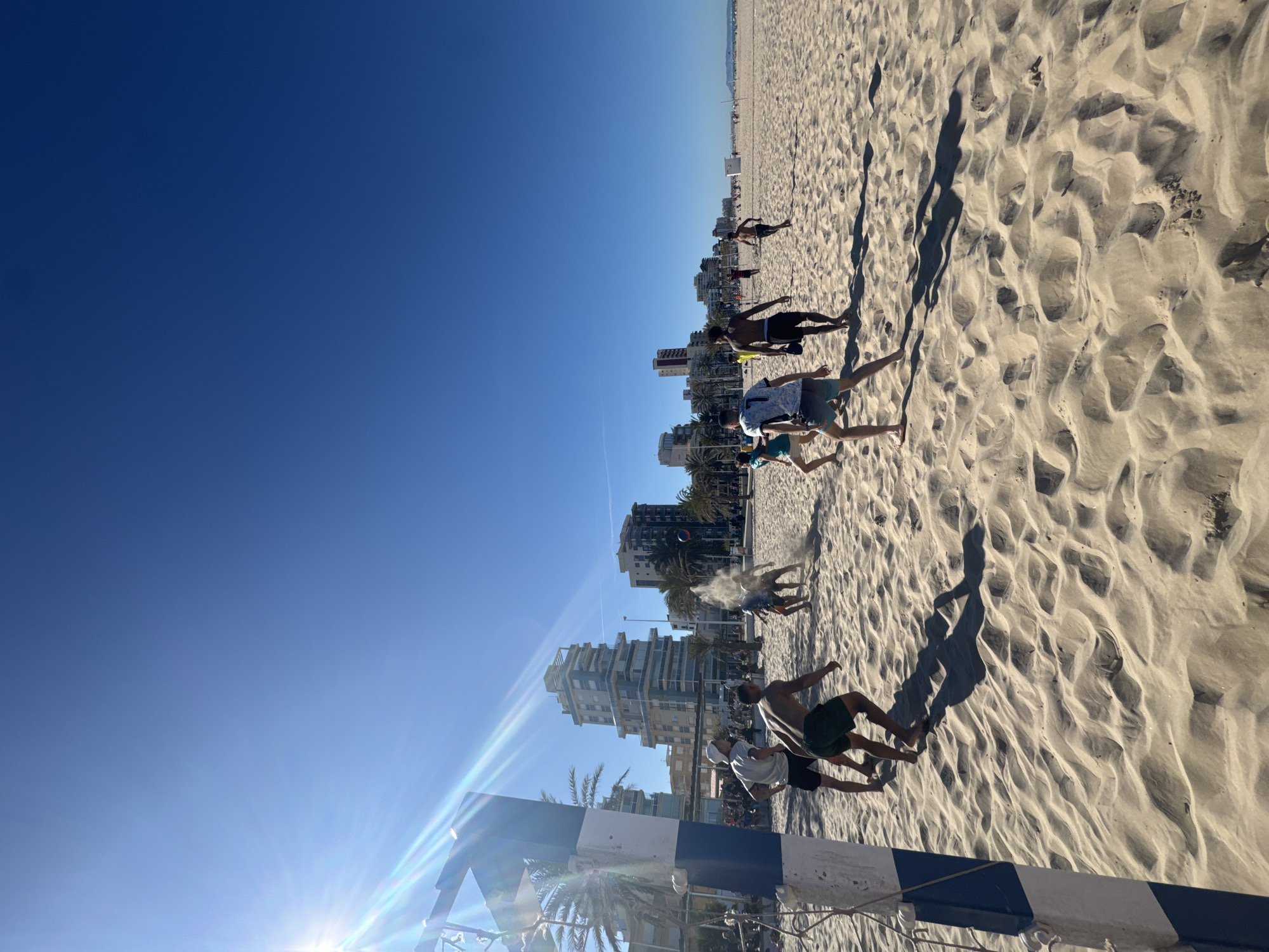 Beachgoer relaxes on crowded Gandia beach during sunny afternoon