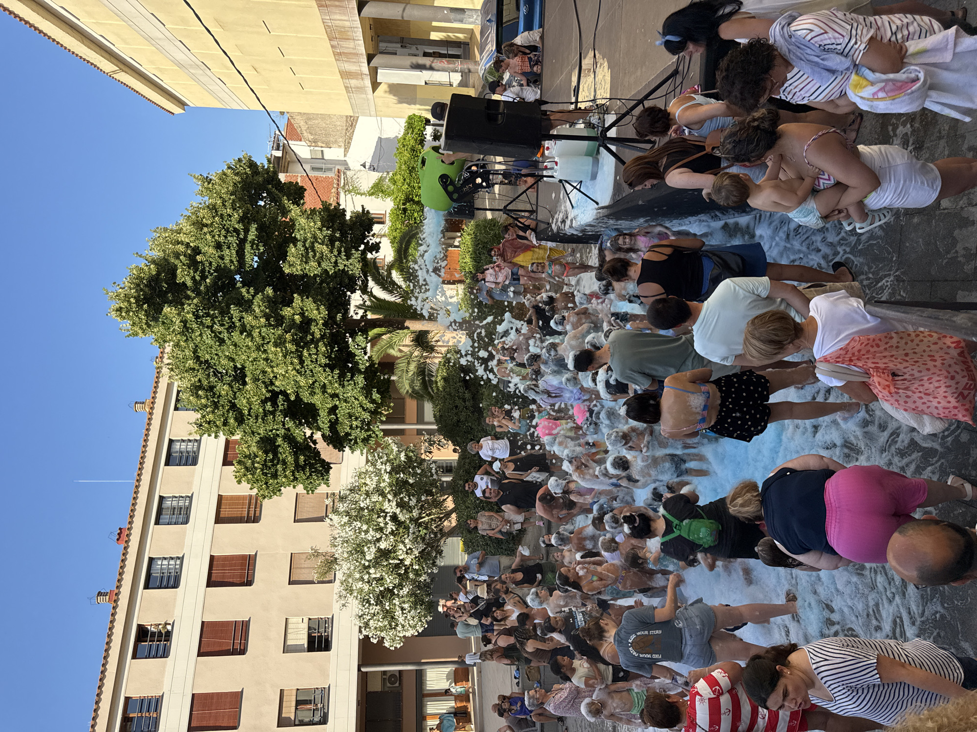 Foam party and street life in Tossa de Mar on a summer afternoon