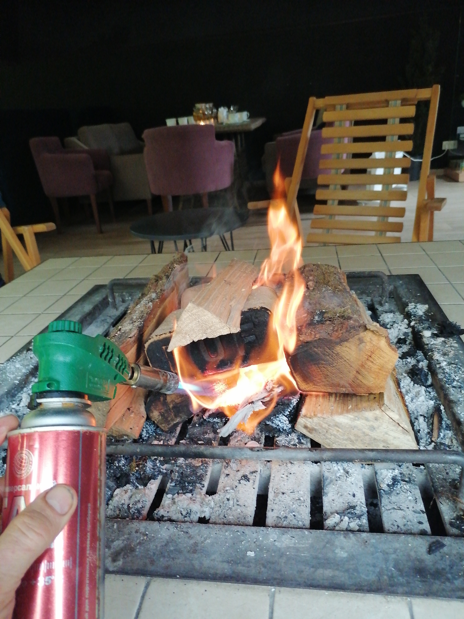 Person lights indoor fireplace with handheld torch