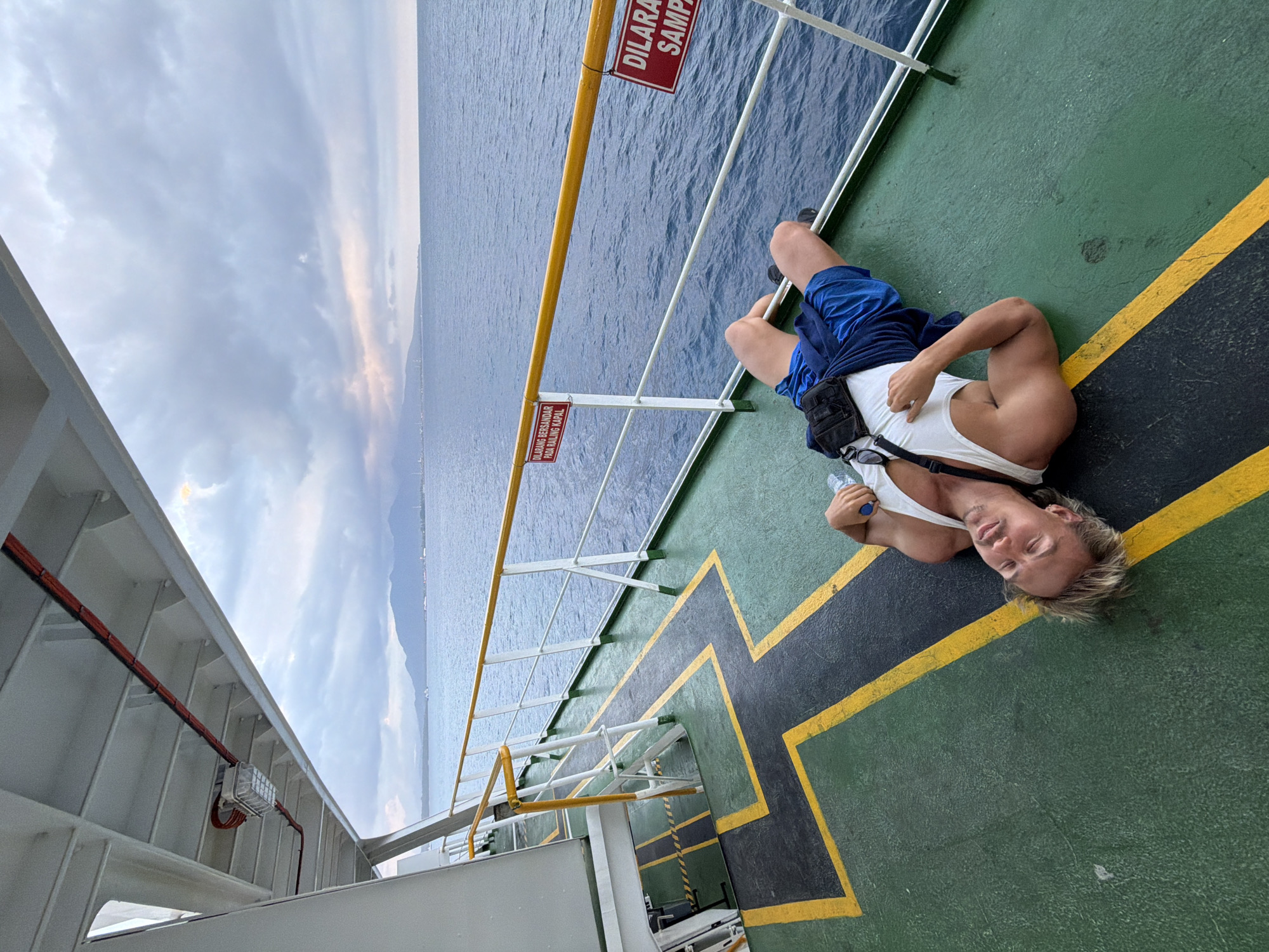 Relaxing on a ferry deck at Ketapang, legs over the water