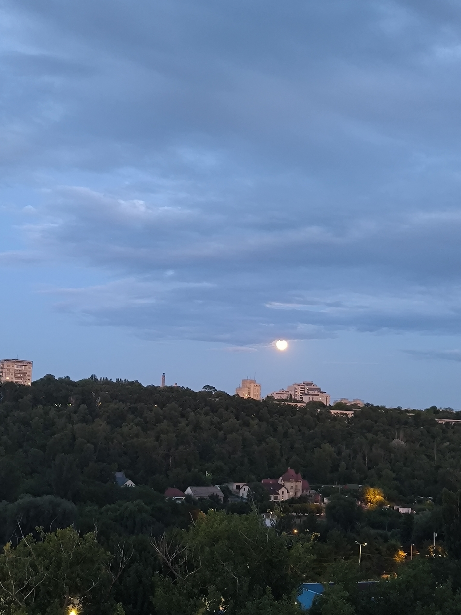 Chișinău at dusk: apartment blocks, storm clouds, and a rising moon