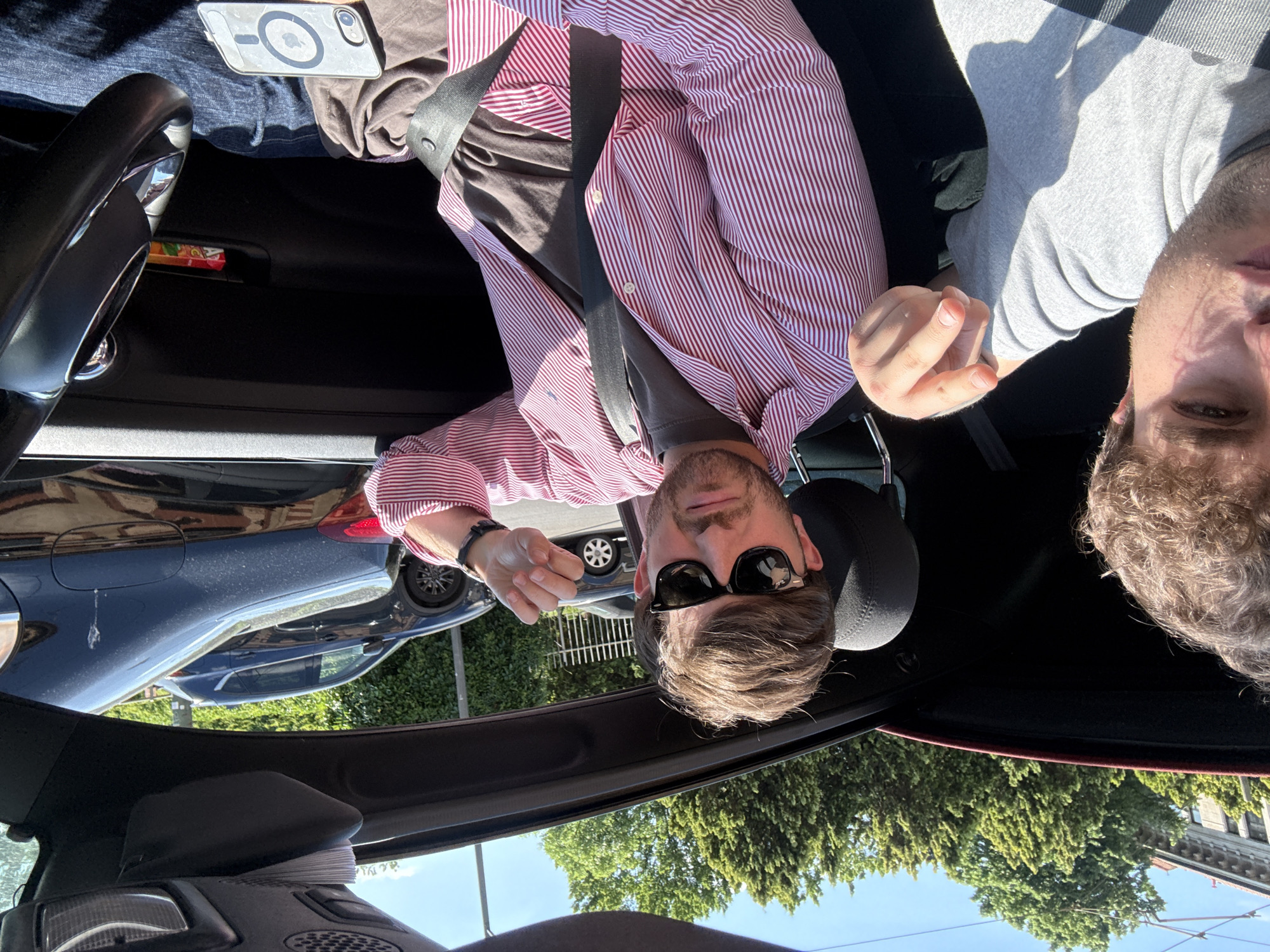 Two people photographed inside car during sunny afternoon in Milan