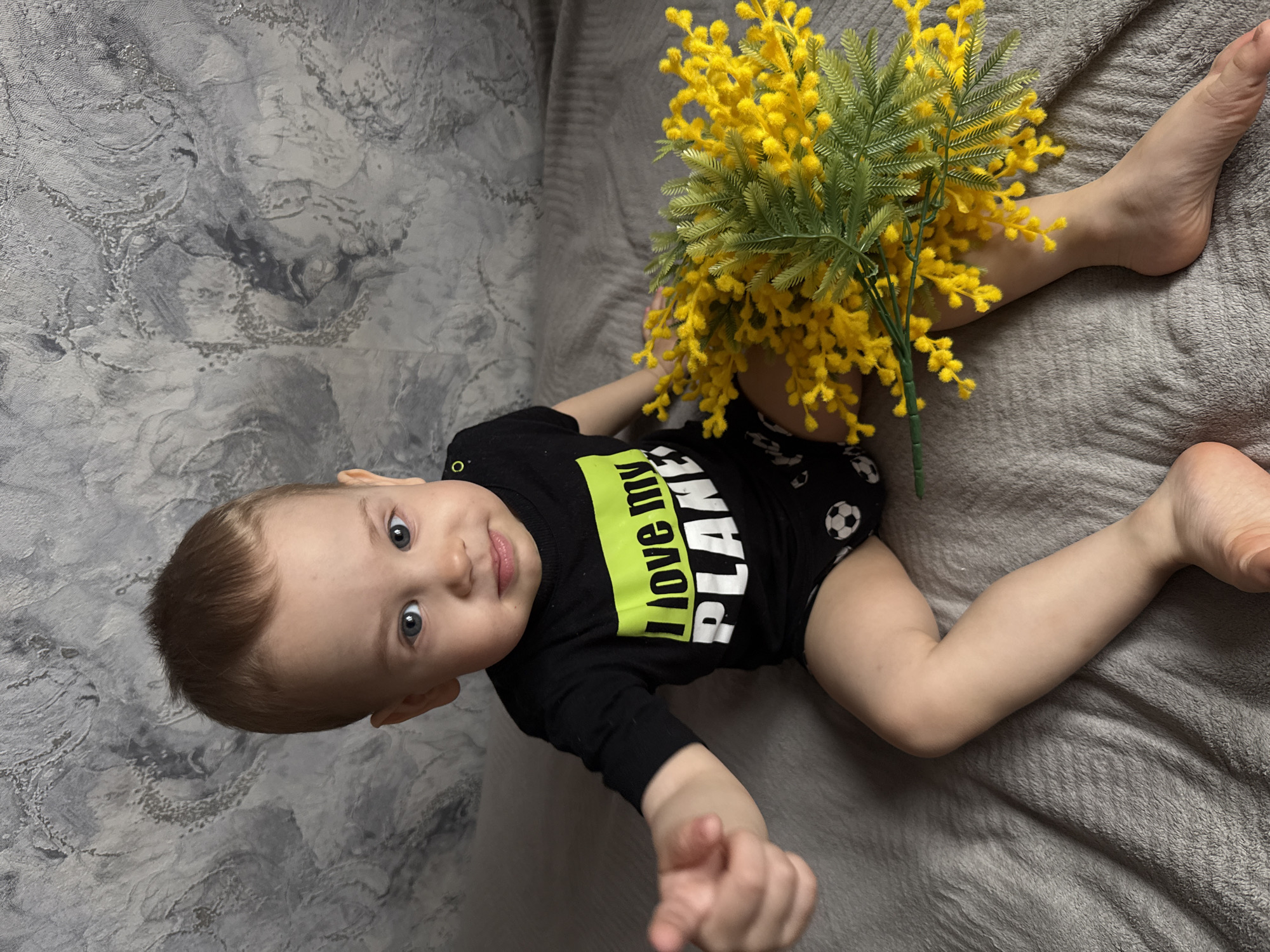 Baby photographed in eco-themed outfit with flower arrangement