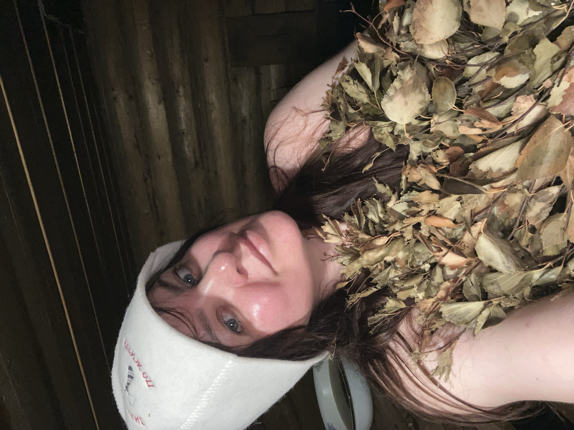 Woman in sauna hat covered with leaves in Protasy