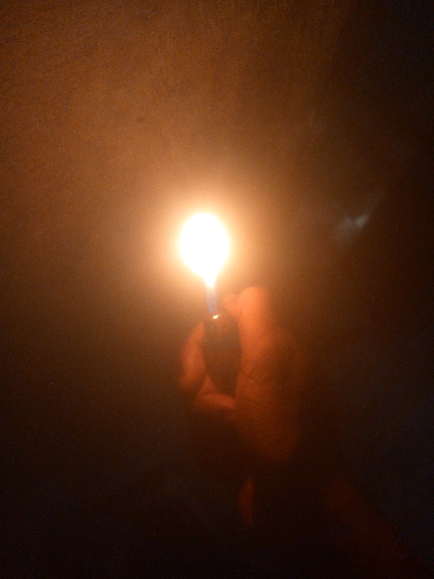 Person uses lighter near electrical outlet in darkness