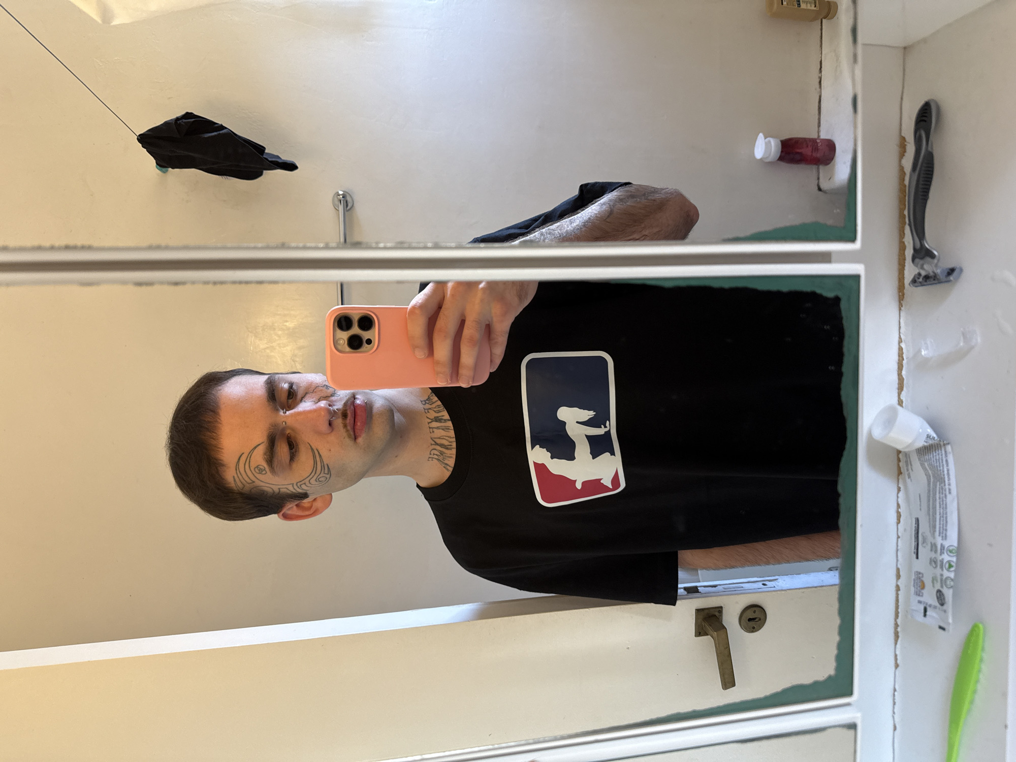 Man with facial tattoos takes bathroom mirror selfie in Buenos Aires