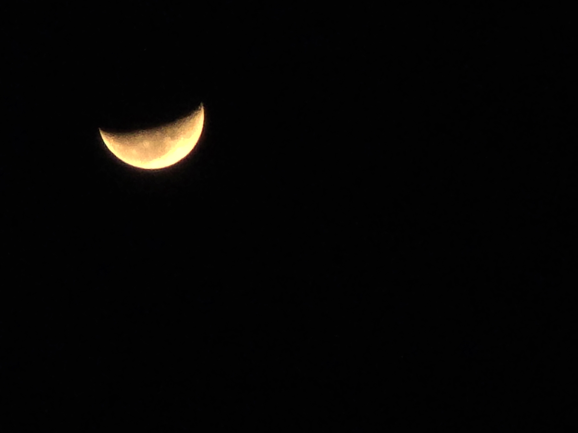 Crescent moon rising over a city at dusk