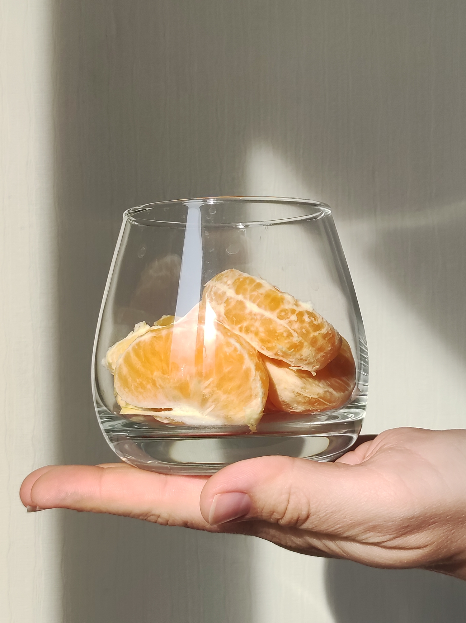 Woman prepares glass of orange segments indoors