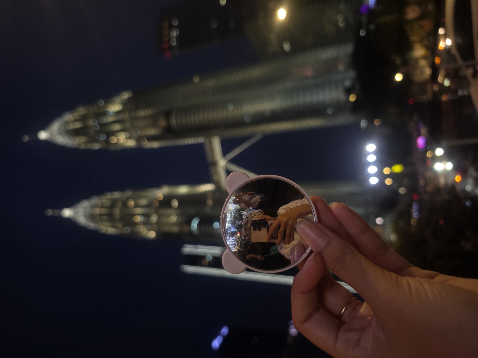 Nighttime photography session captures handheld objects against Kuala Lumpur skyline