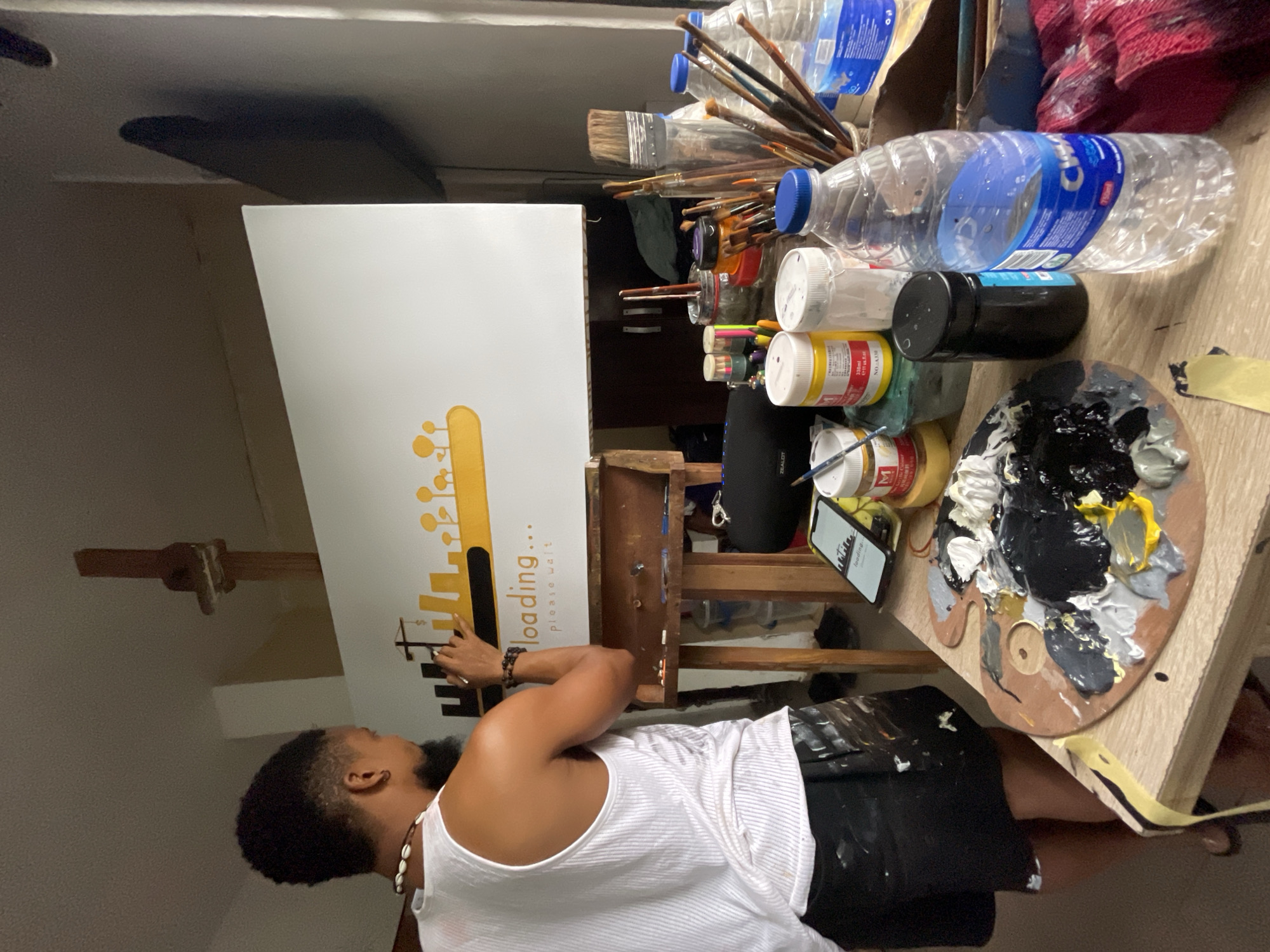 Artist paints "loading" cityscape canvas in Ado studio