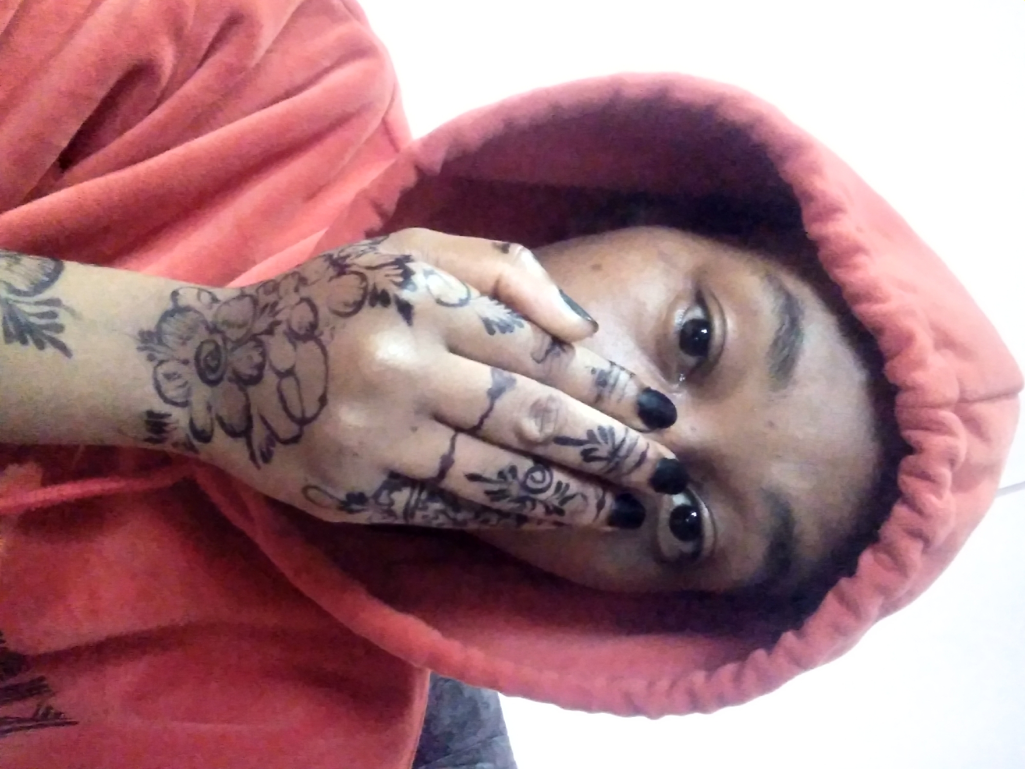 Person in orange hoodie with henna tattoos documented