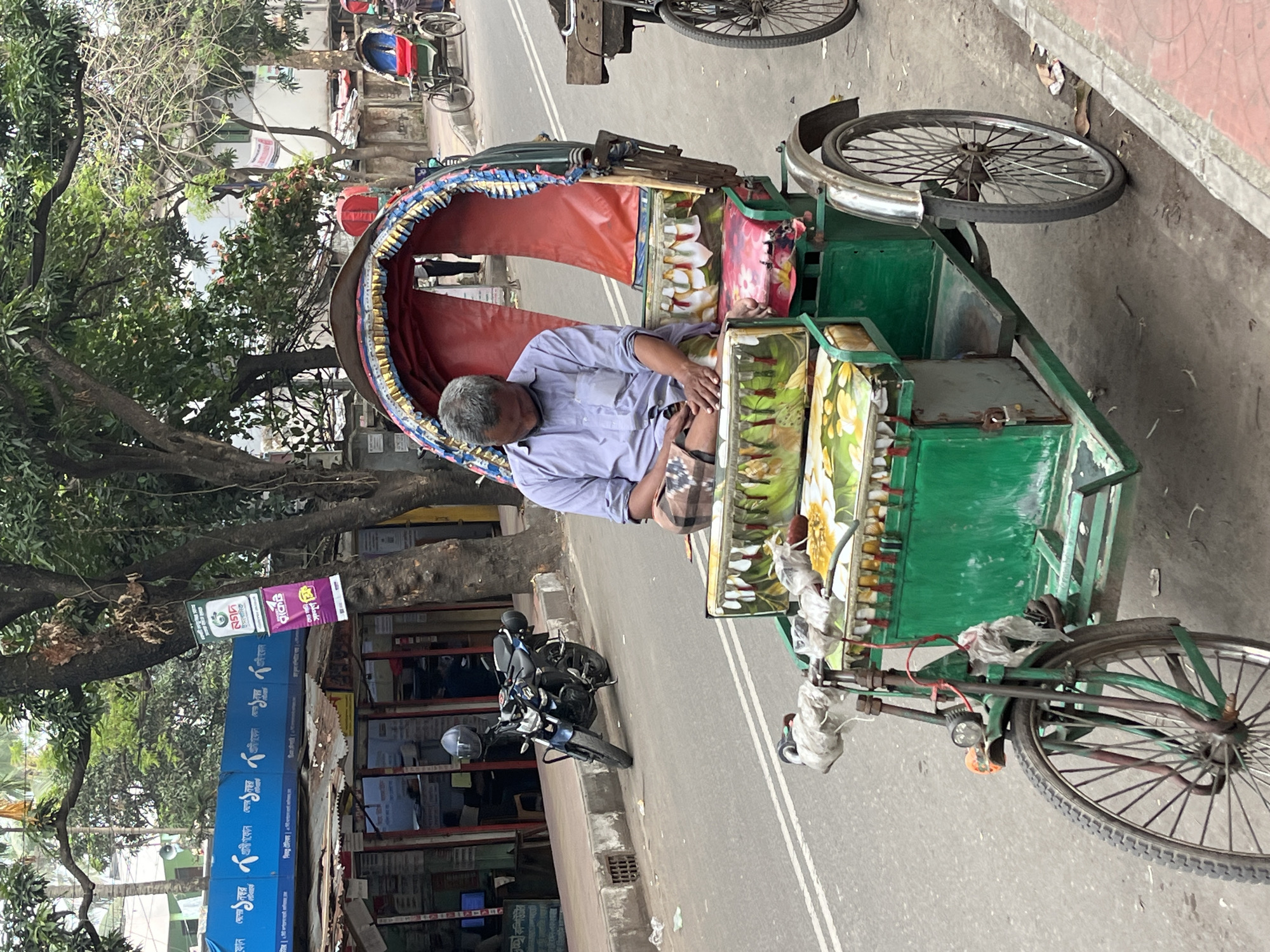 Man sleeps in decorated rickshaw on Dhaka street