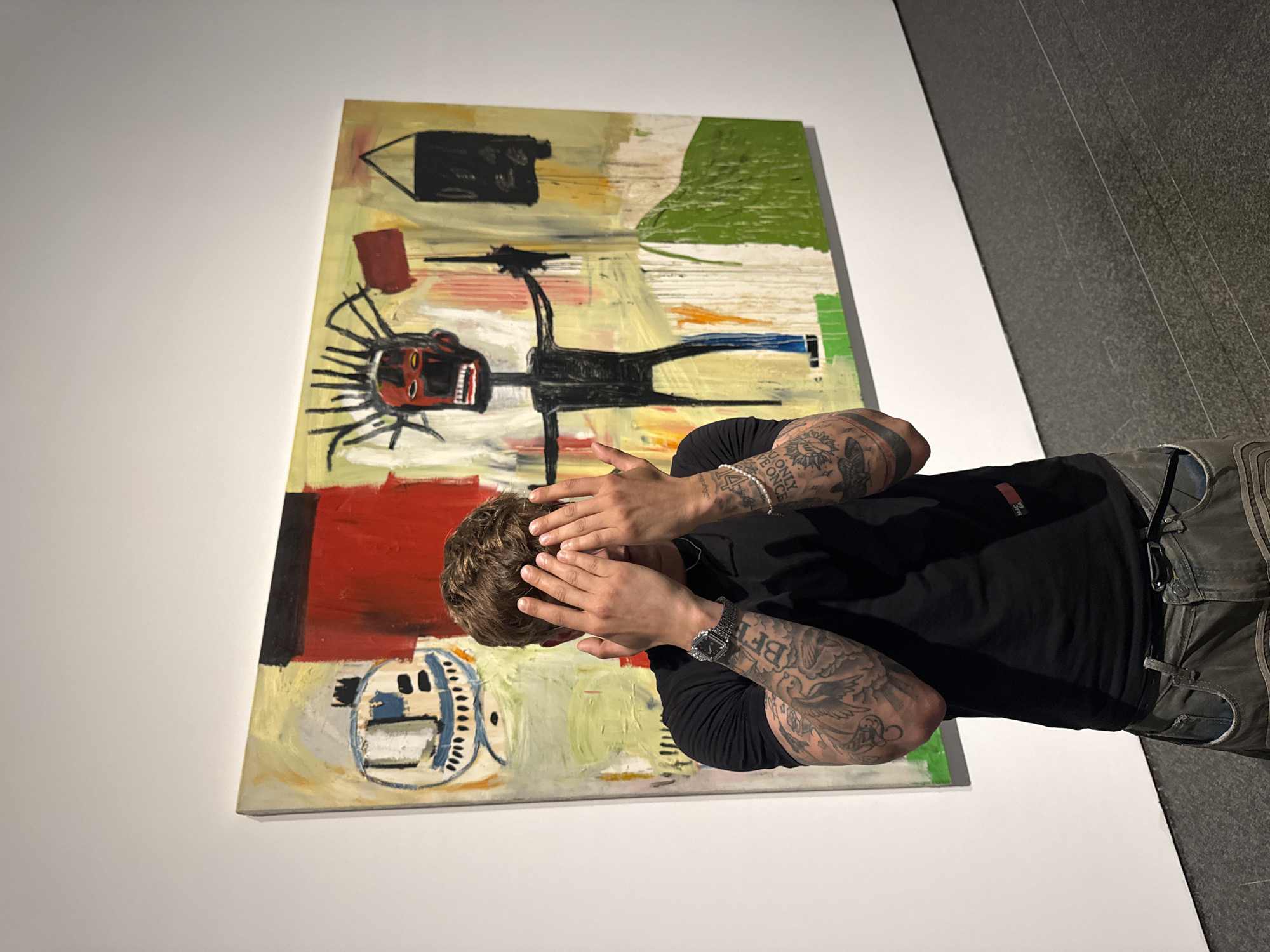 Tattooed figure poses before abstract art in Barcelona gallery