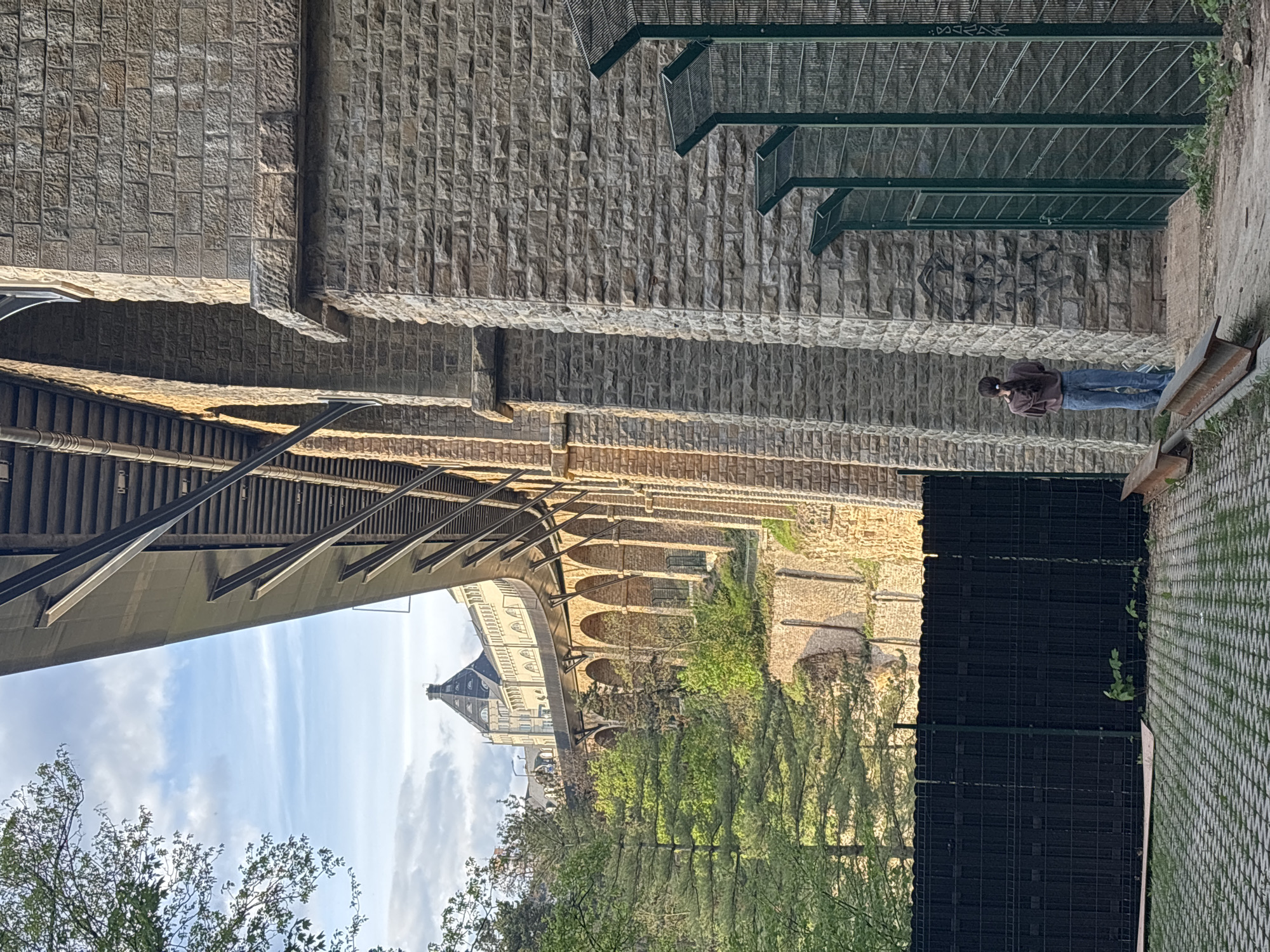 Woman stands beneath stone bridge in Luxembourg's Grund district