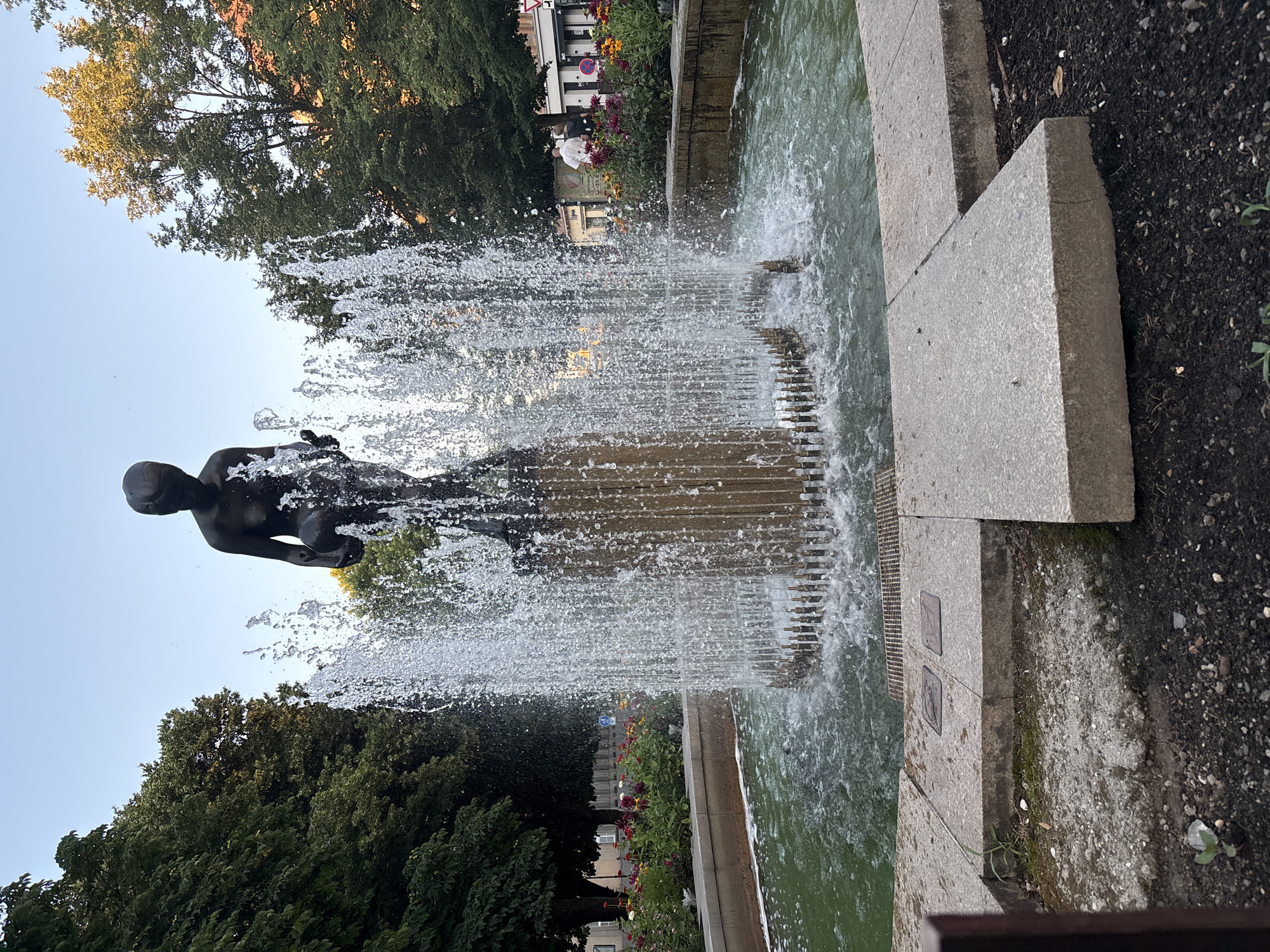 Pilsen park fountains, flowers, and statues on a summer evening