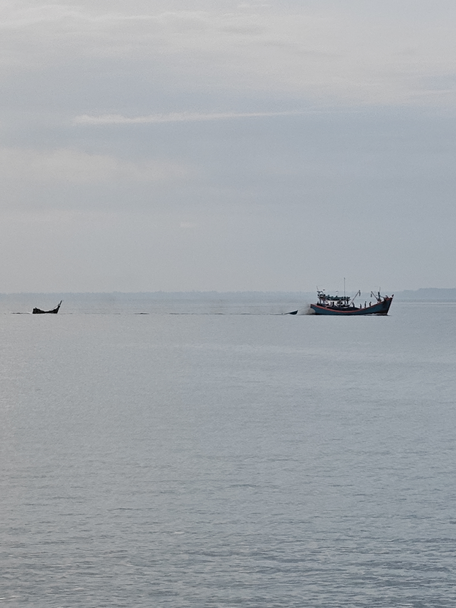 Lhokseumawe waterfront at dusk: pier, fishing boats, and shoreline