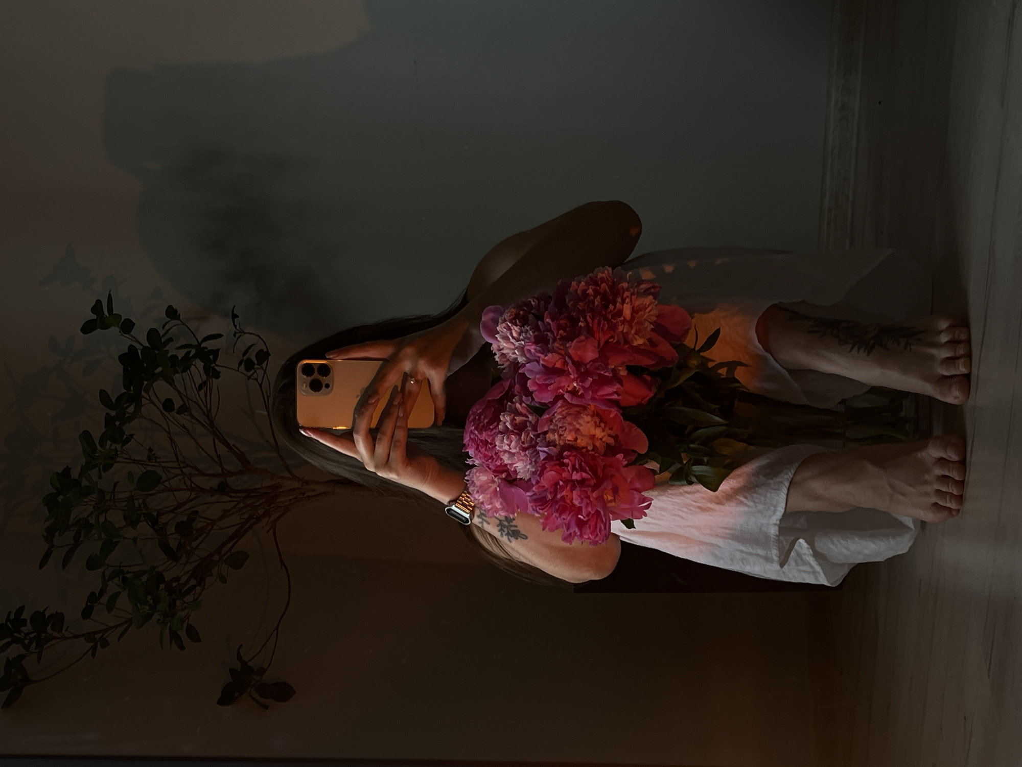 Woman takes selfies with pink peonies in Ternopil room