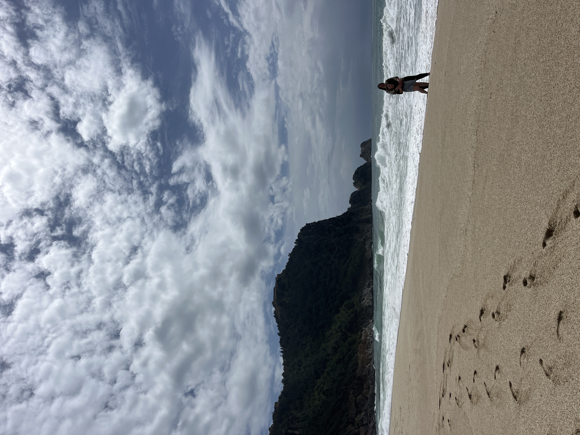 Two people stand at water's edge on Alanya beach