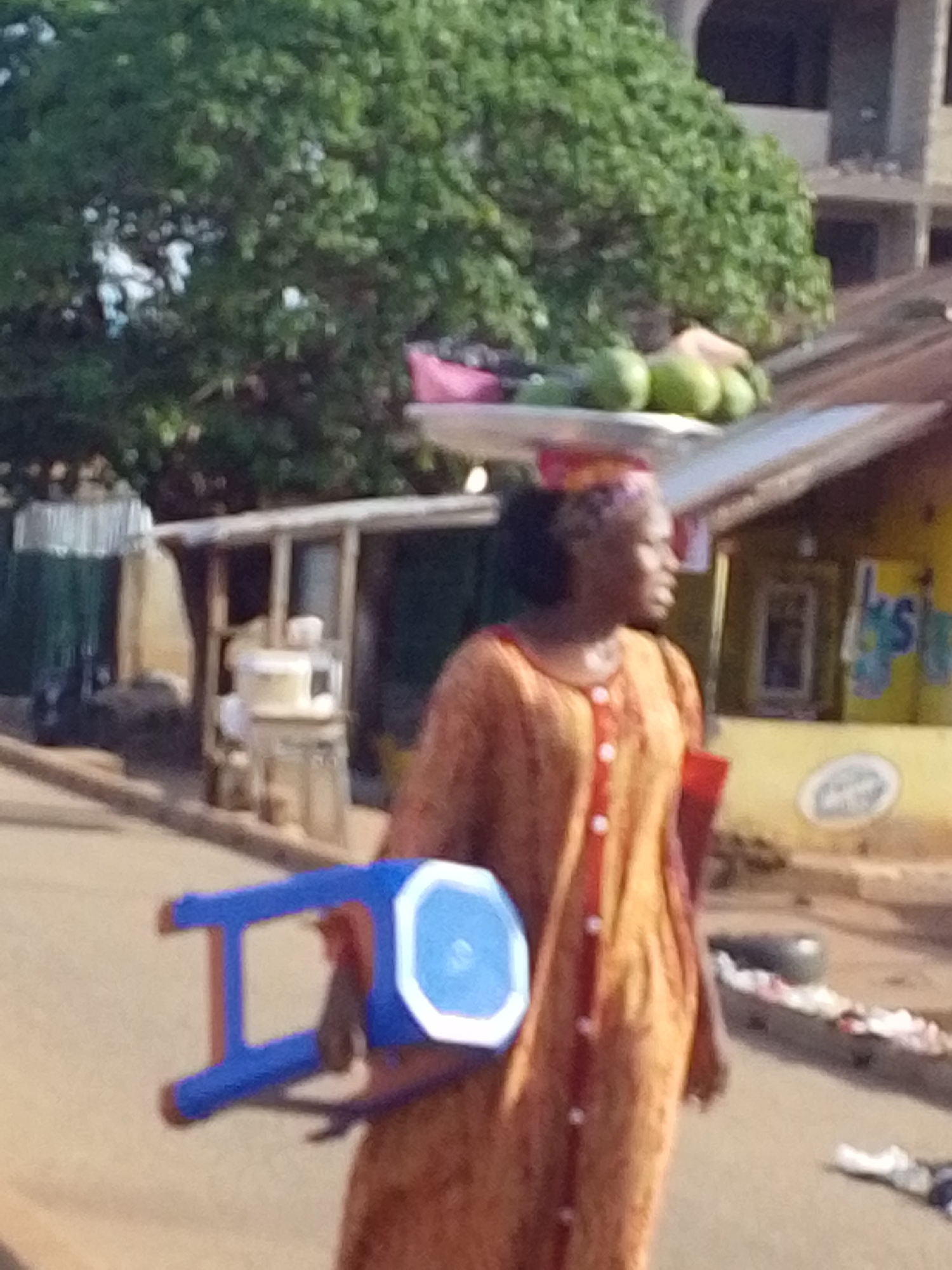 Woman carries fruit tray on head through Tamale streets