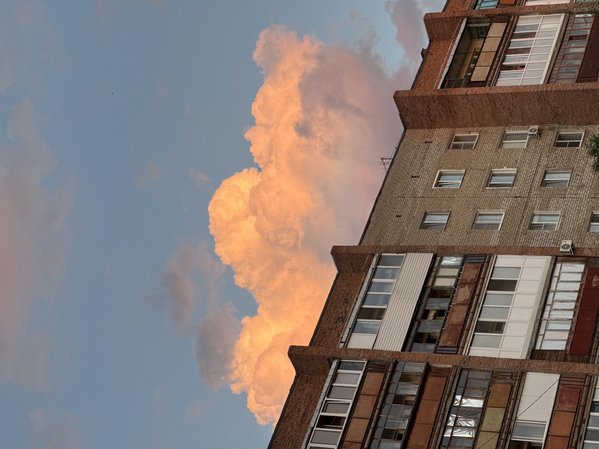 Brick apartment block against a peachy sunset sky in Omsk