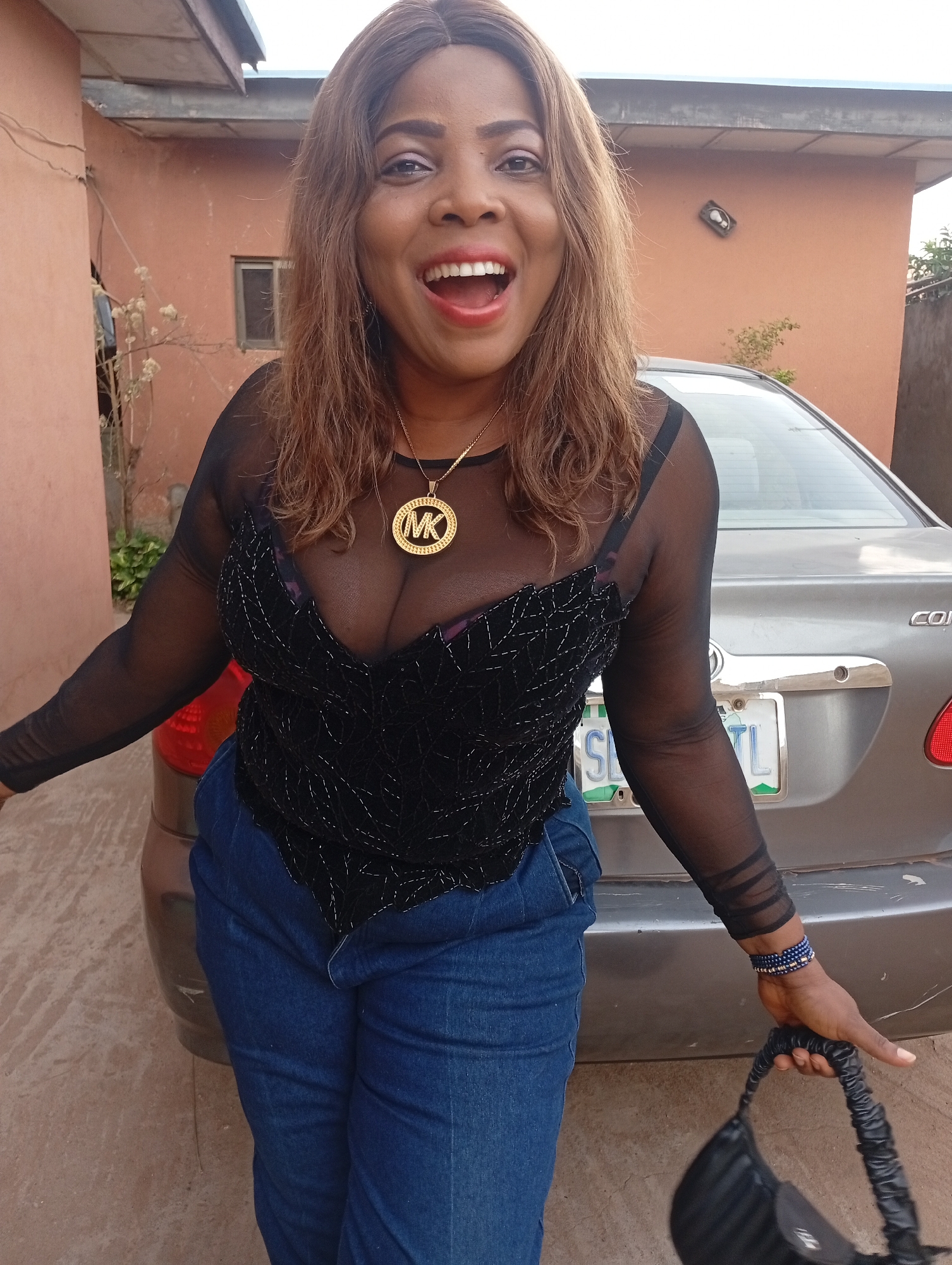 Woman in red photographed outside green building in Nigeria