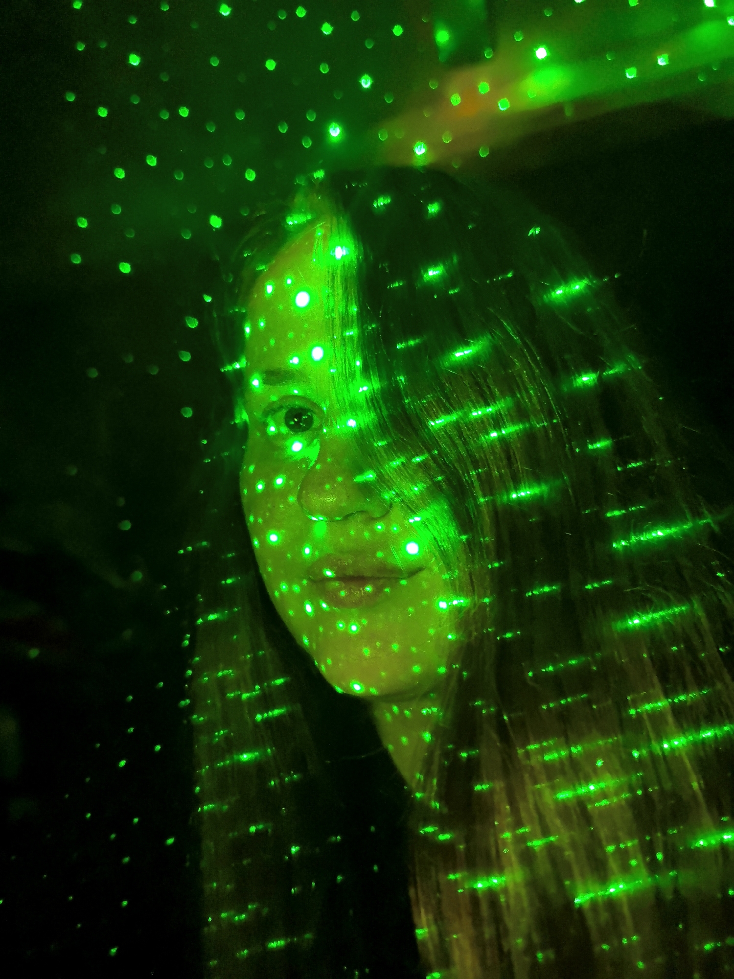 Person and hand captured in green laser light display