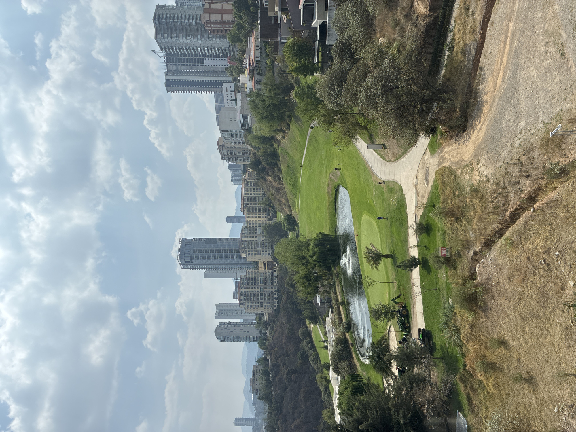 Person smoking at elevated viewpoint overlooking Huixquilucan golf course