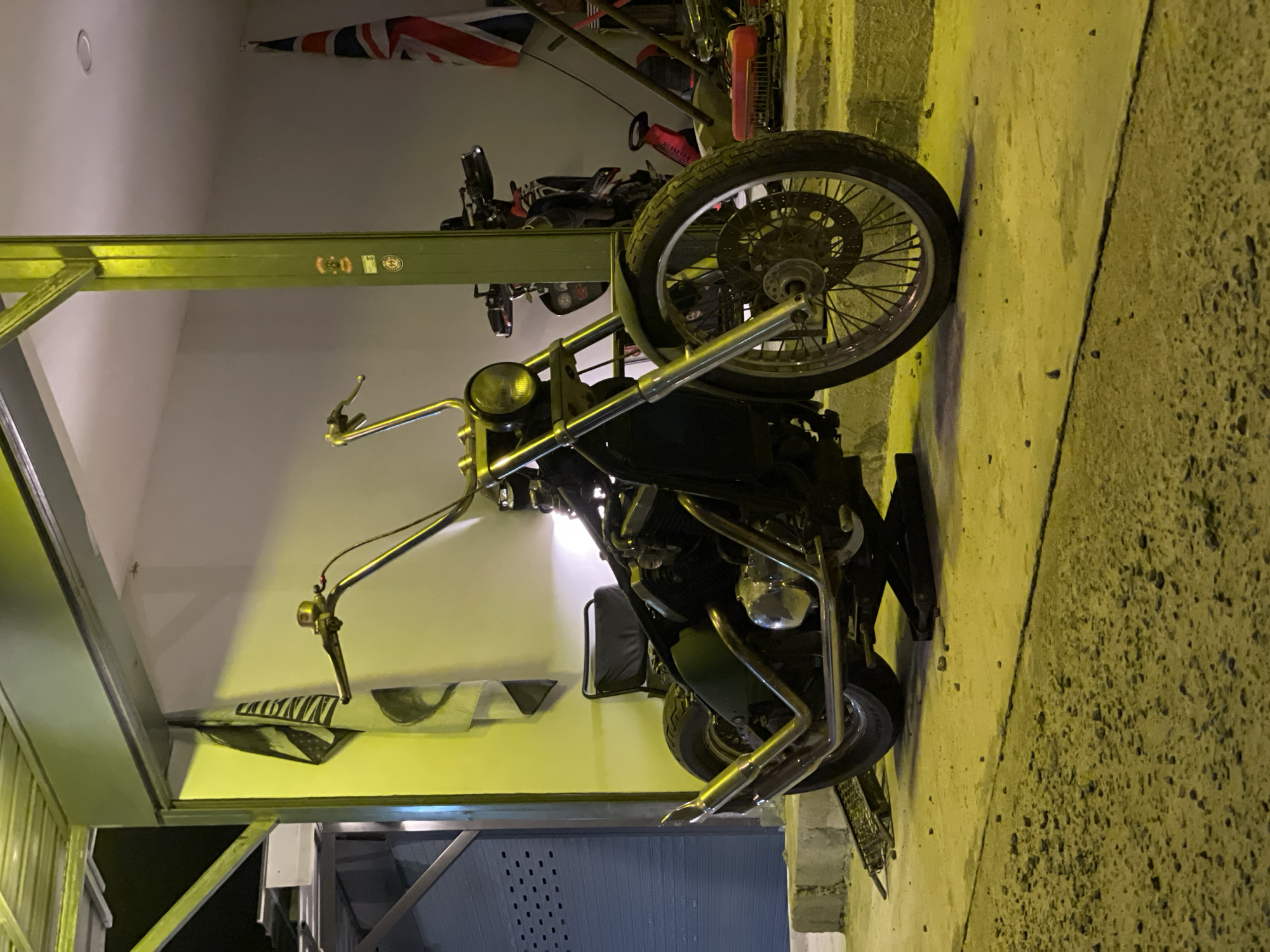 Black motorcycle parked in garage with British flag backdrop